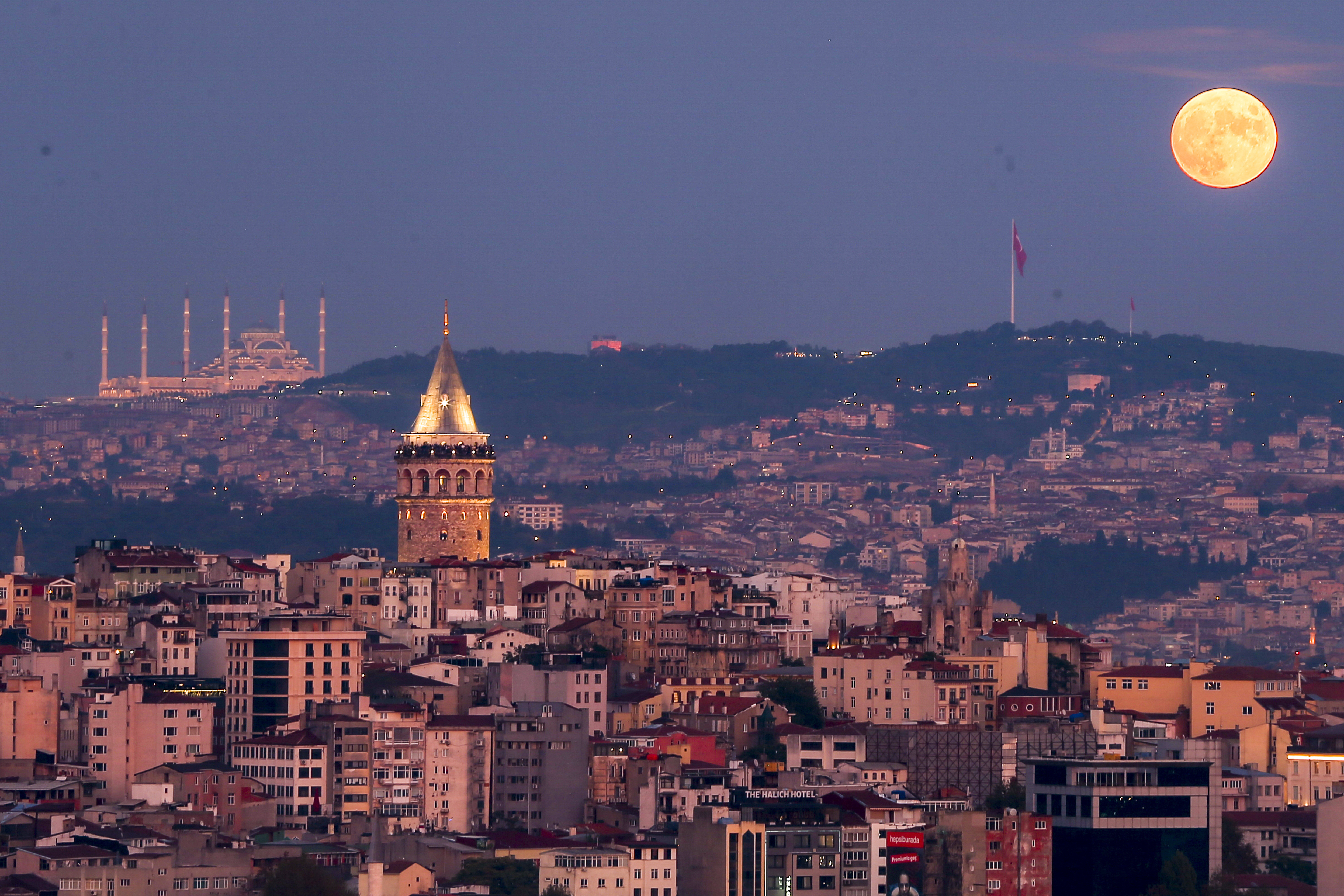 A full moon rises behind the Galata tower