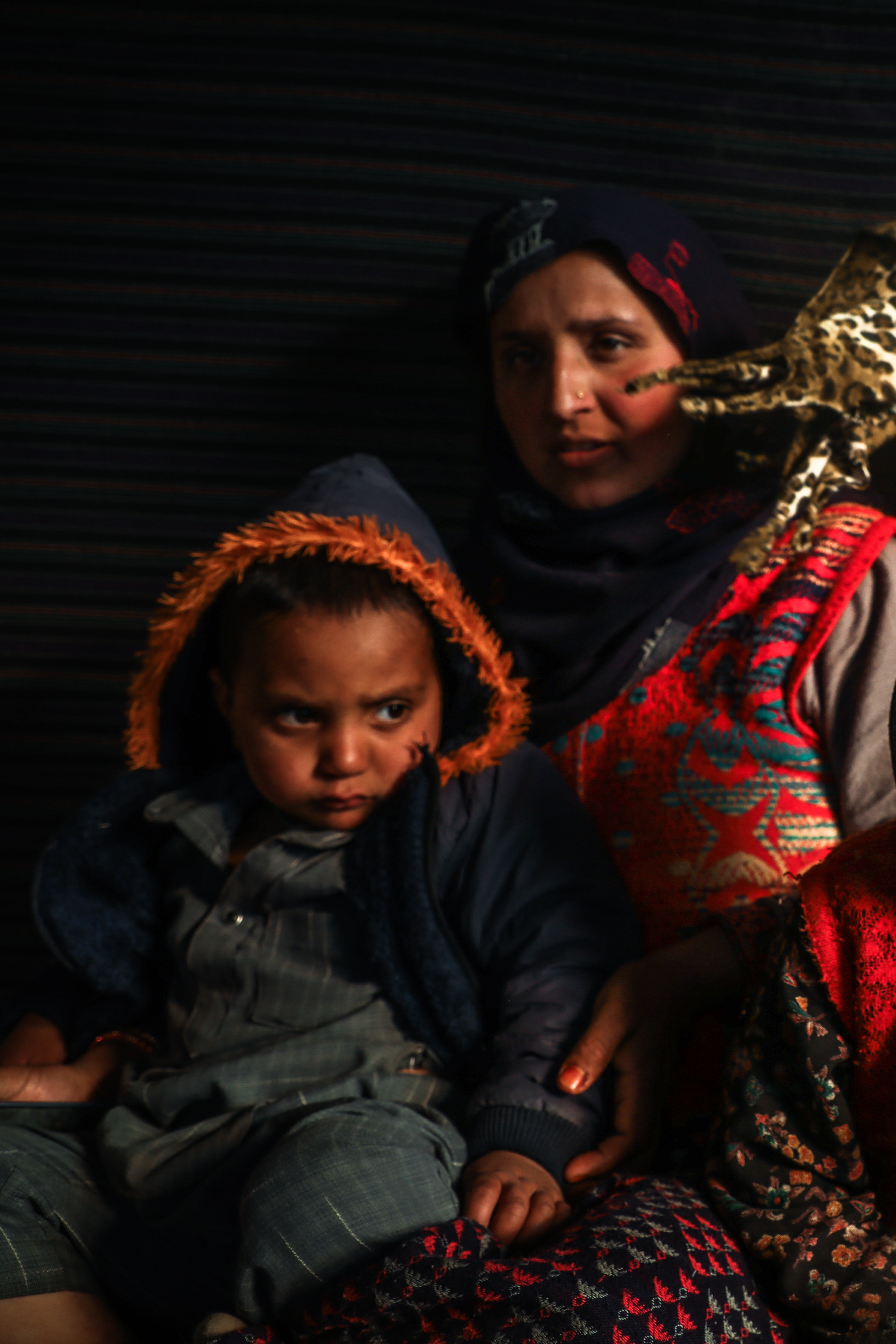 Shameem Kounsar, 26, holds her son, Usman, the youngest deaf-mute person on the village (left), while sitting with children from the family