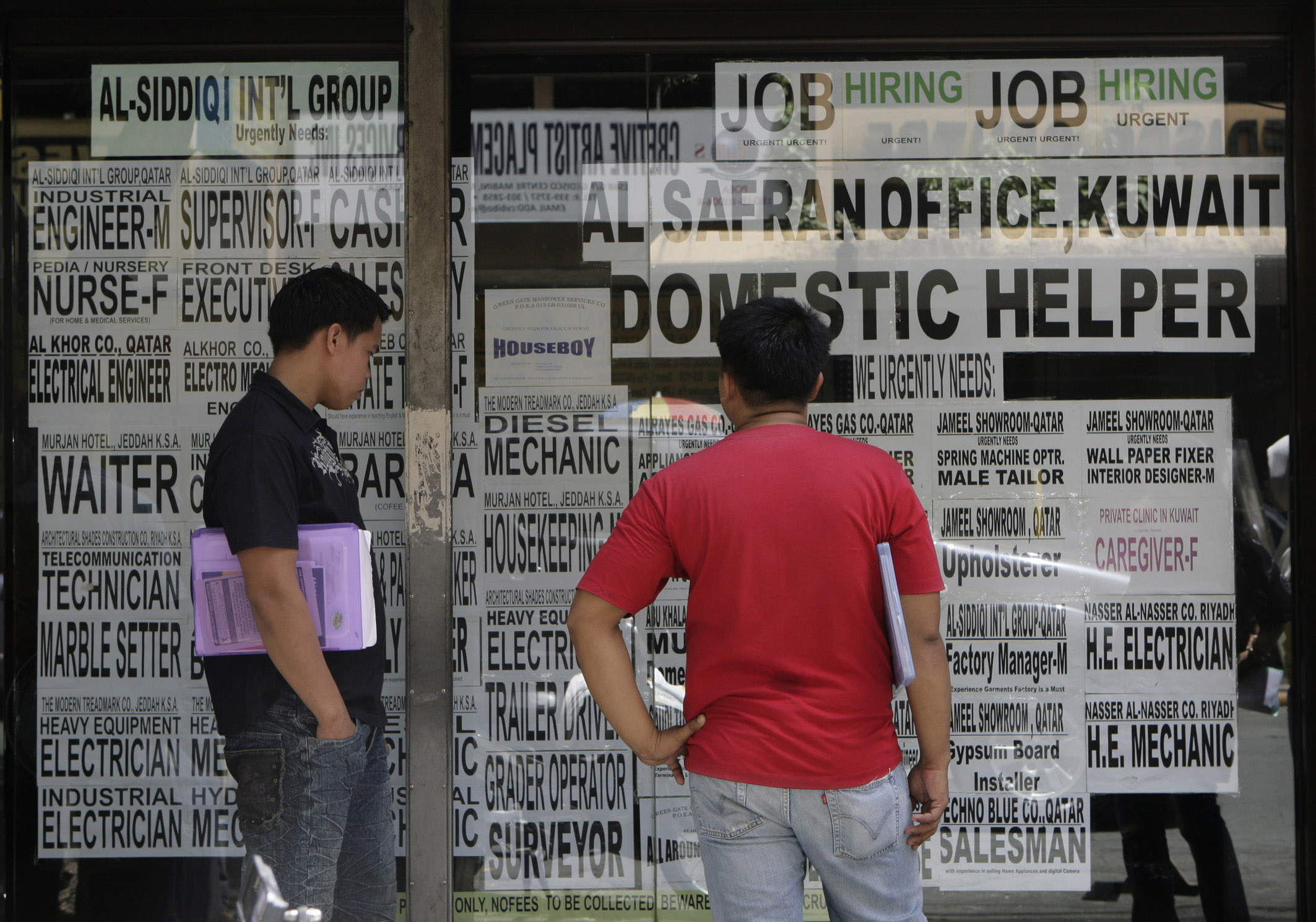 People seeking jobs overseas read ads outside a recruitment agency in Manila June 26, 2009. The Philippines' jobless rate slipped to 7.5 percent in April from 7.7 percent in January despite the economy shrinking at fastest pace in two decades in the first three months of the year, data showed. REUTERS/Erik de Castro (PHILIPPINES EMPLOYMENT BUSINESS)