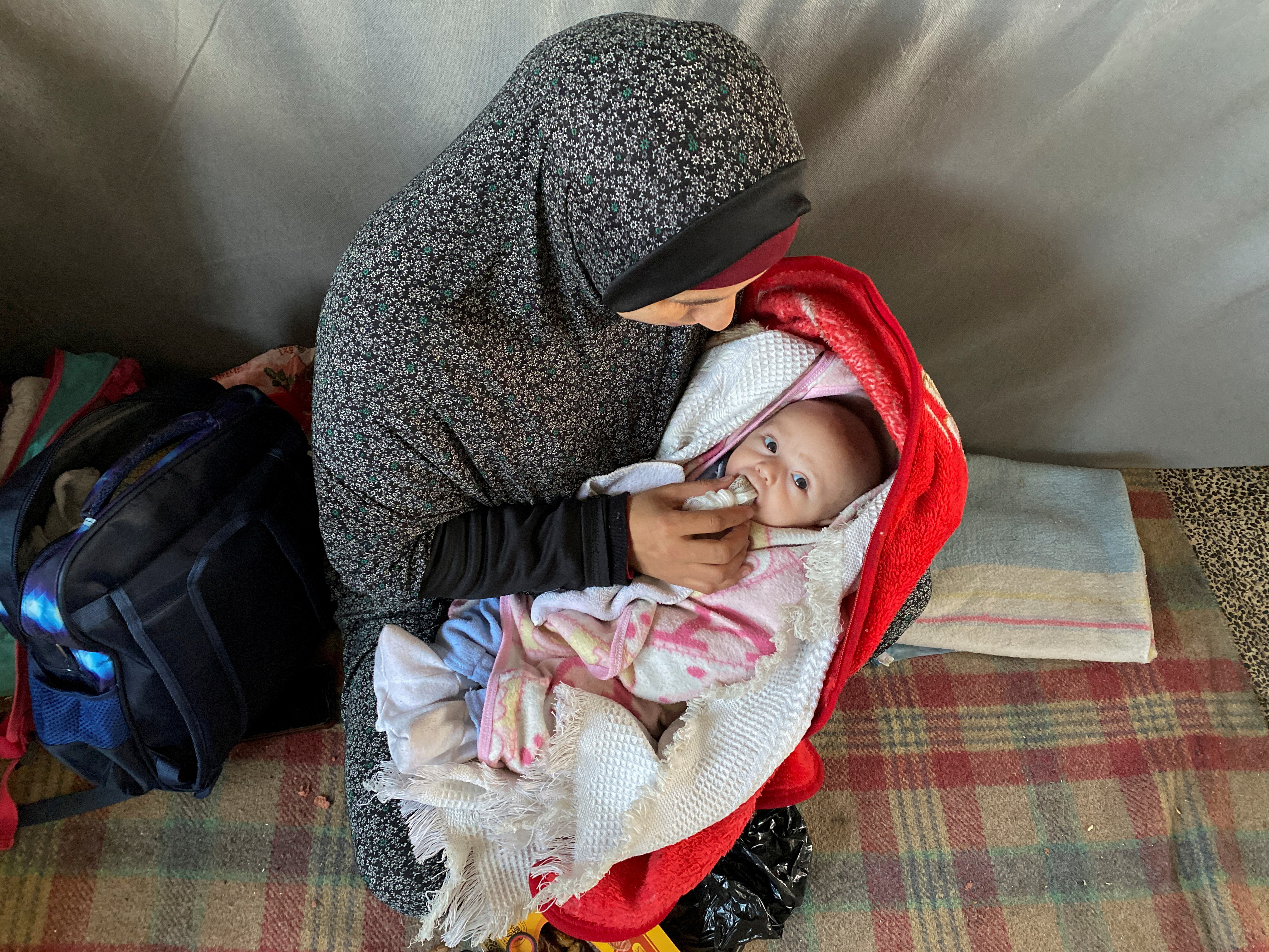 Palestinian woman Warda Mattar feeds her newborn dates, instead of milk, amidst food scarcity and lack of milk, at a school where they shelter in Nuseirat in the central Gaza Strip February 25