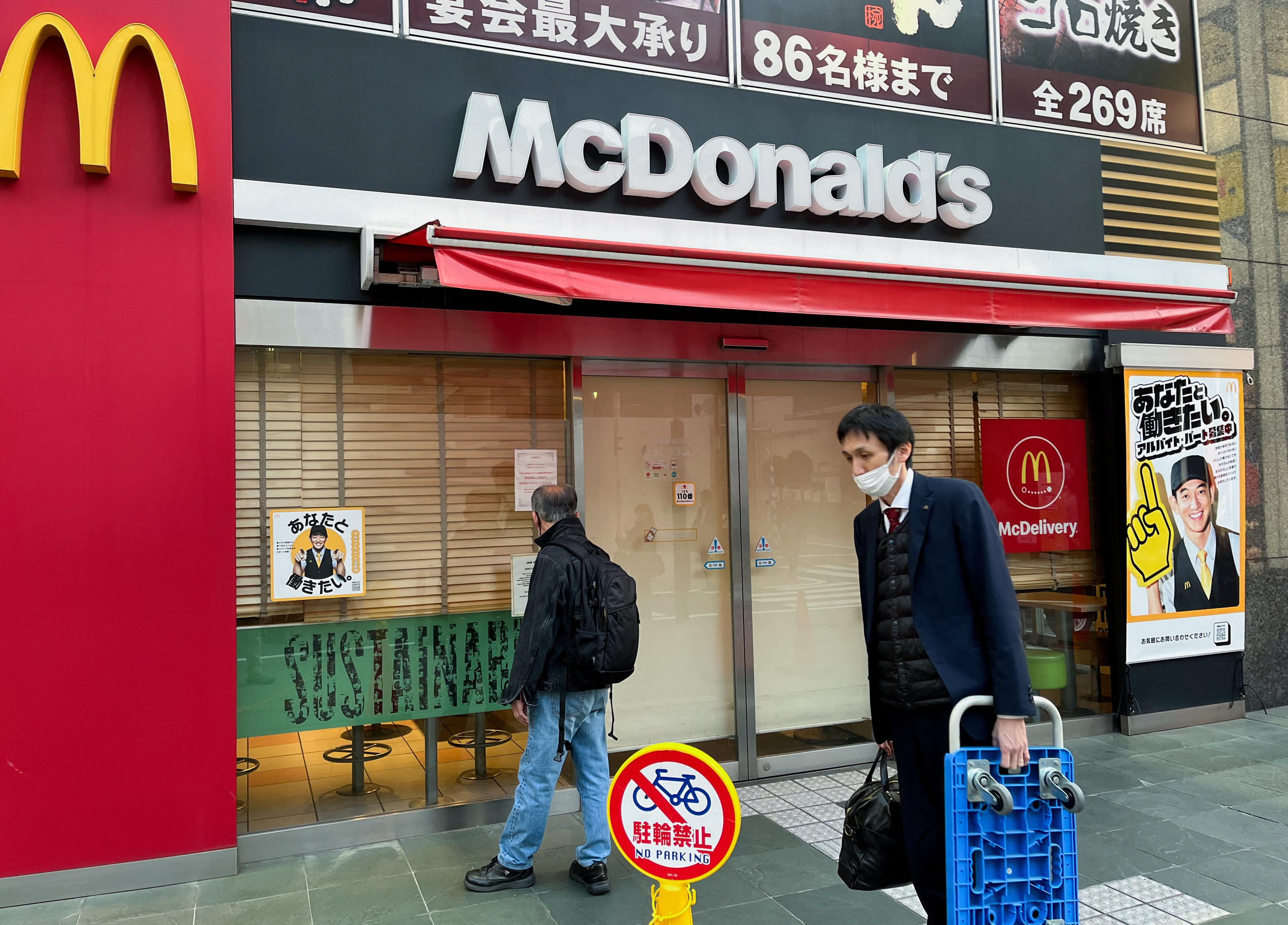 A man reads a notice in the window of a closed McDonald's restaurant as the company said it halted operations due to a system disruption, in Tokyo, Japan, on March 15, 2024