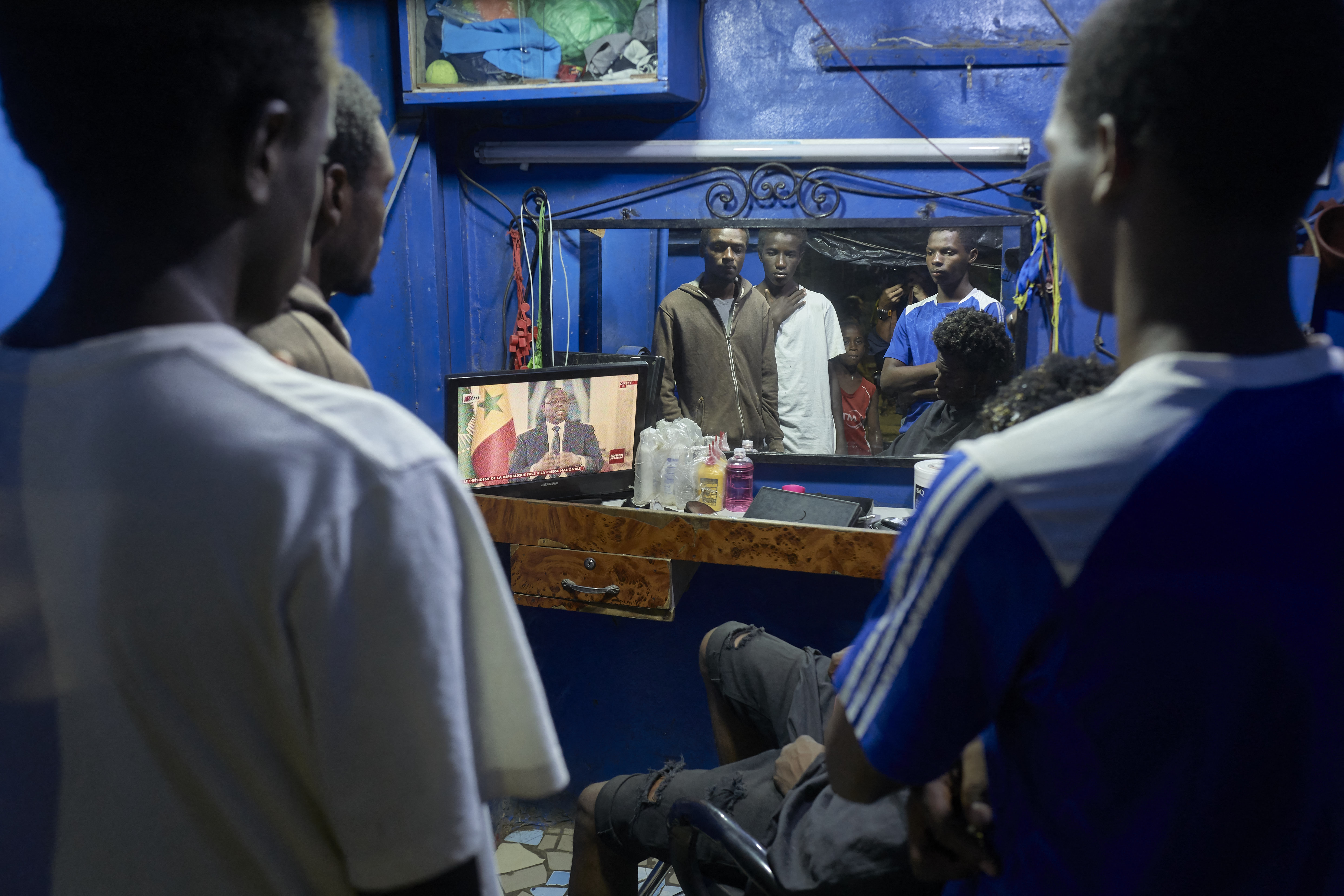 People watch Senegal's President Macky Sall on TV during a live press conference.
