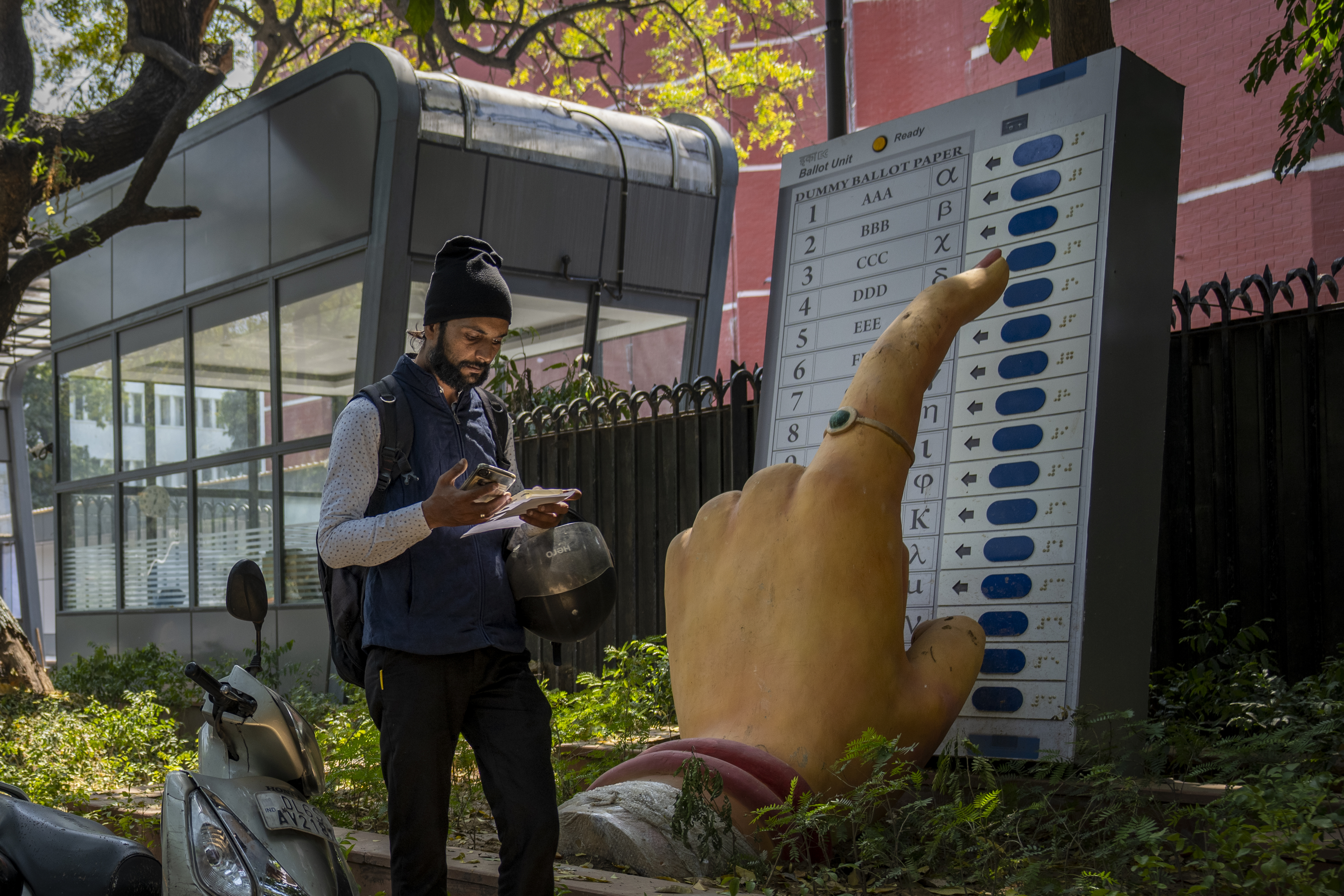 A man walks past a large model of a woman's finger pressing a button of an electronic voting machine displayed outside the office of Election Commission of India in New Delhi, India, Wednesday, March 20, 2024. From April 19 to June 1, nearly 970 million Indians - or over 10% of the world's population - will vote in the country's general elections. The mammoth electoral exercise is the biggest anywhere in the world - and will take 44 days to complete before results are announced on June 4. (AP Photo/Altaf Qadri)