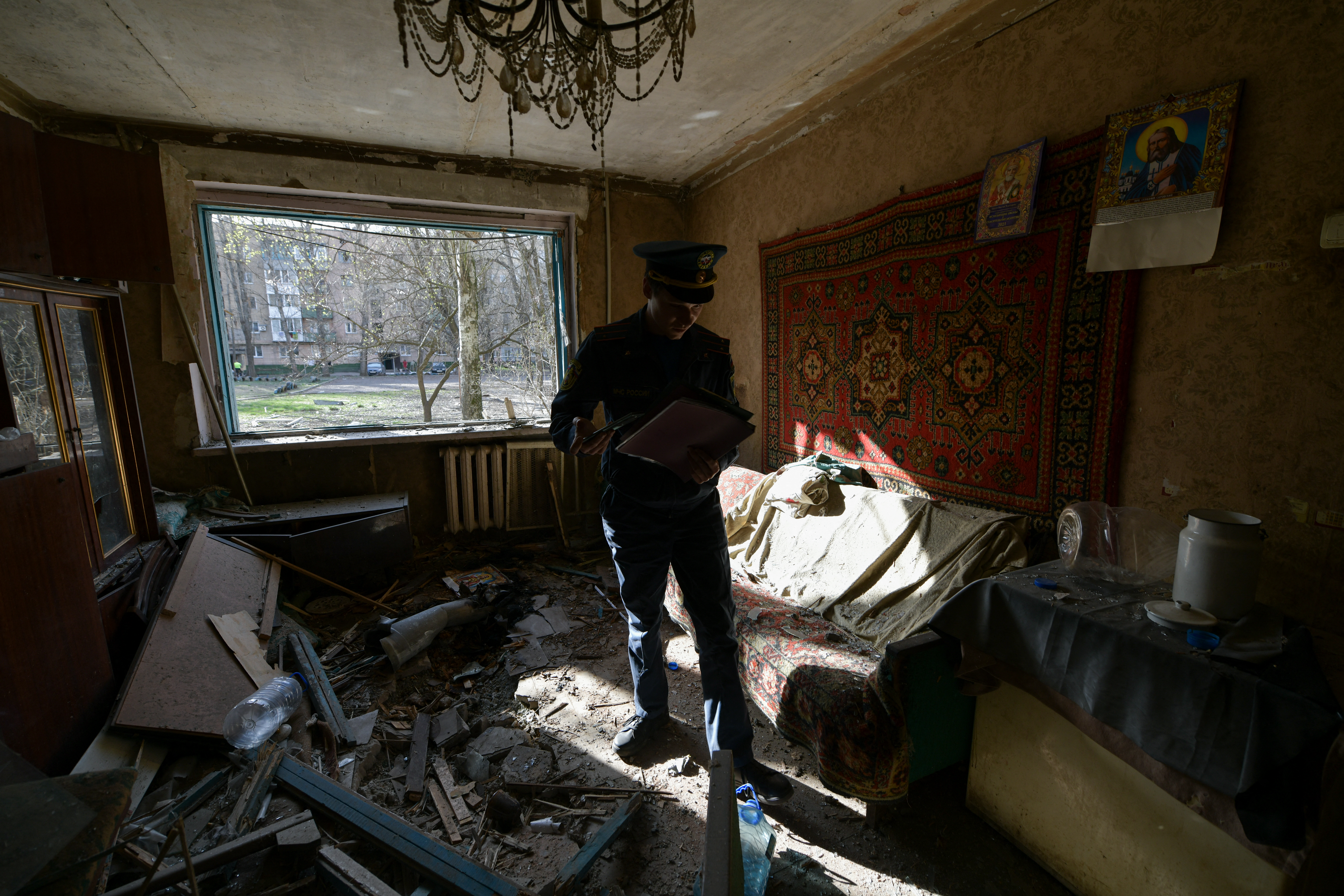A Russian emergencies ministry member inspects damage to a flat in an apartment block hit by recent shelling, what local officials called a Ukrainian military strike, in Donetsk, Russian-controlled Ukraine, on April 4, 2024, amid ongoing Russian-Ukrainian conflict. (Photo by STRINGER / AFP)