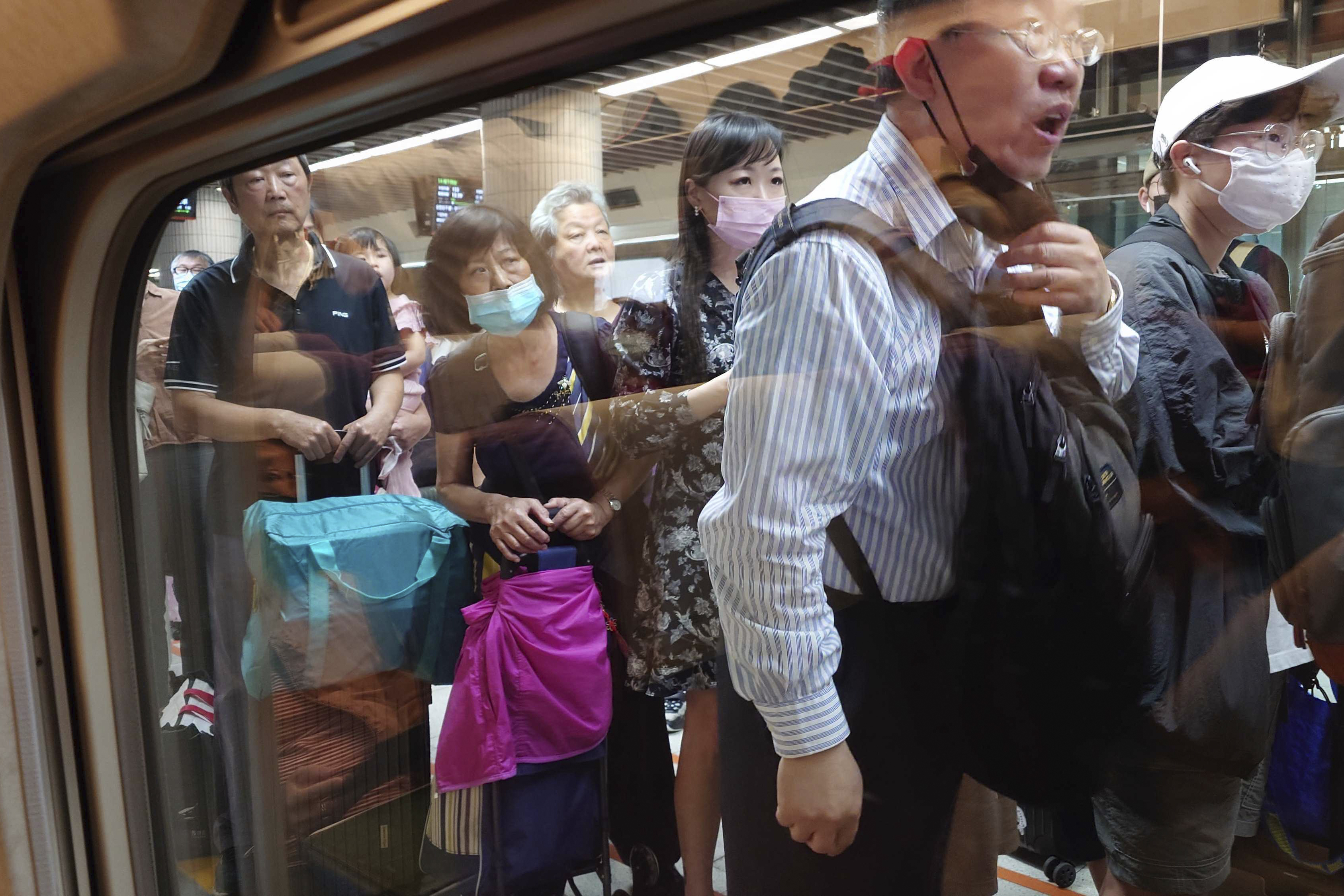 Passengers wait to board a south bound train as some train services were suspended in the aftermath of an earthquake in Taipei, Taiwan