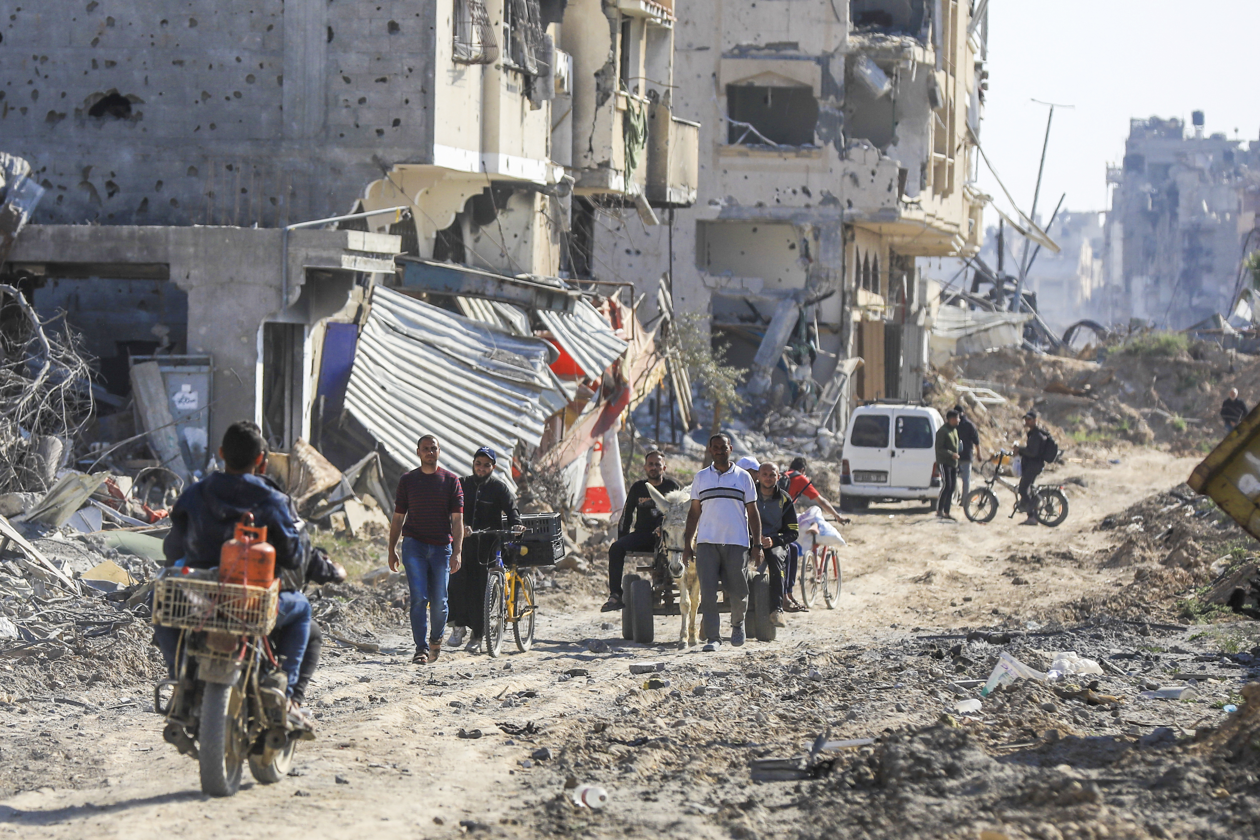 Palestinians walk through the destruction left by the Israeli air and ground offensive after they withdrew from Khan Younis