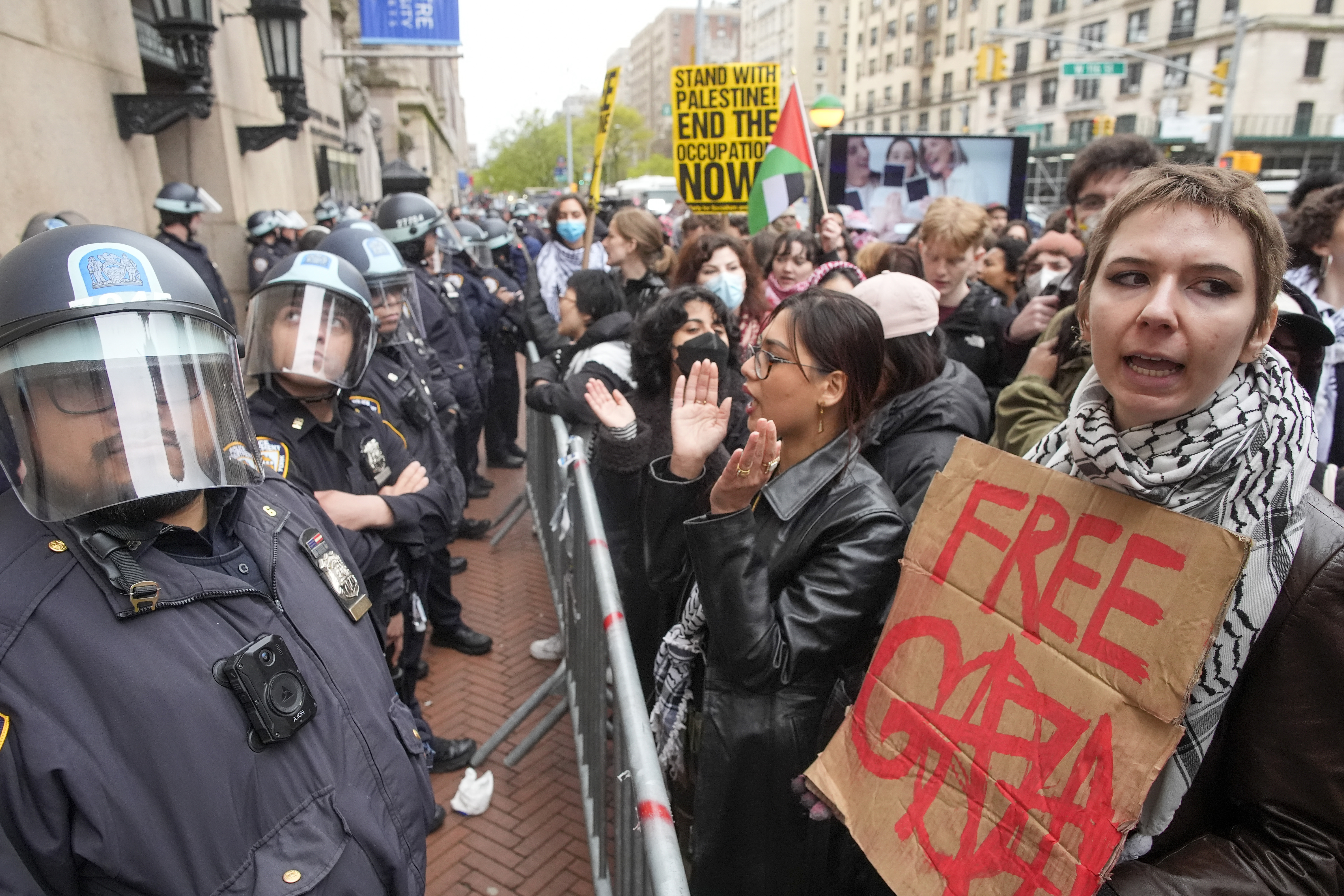 Protesters outside Columbia University in New York. One is carrying a placerd reading Free Gaza. They are behind some barriers. Police are watching.
