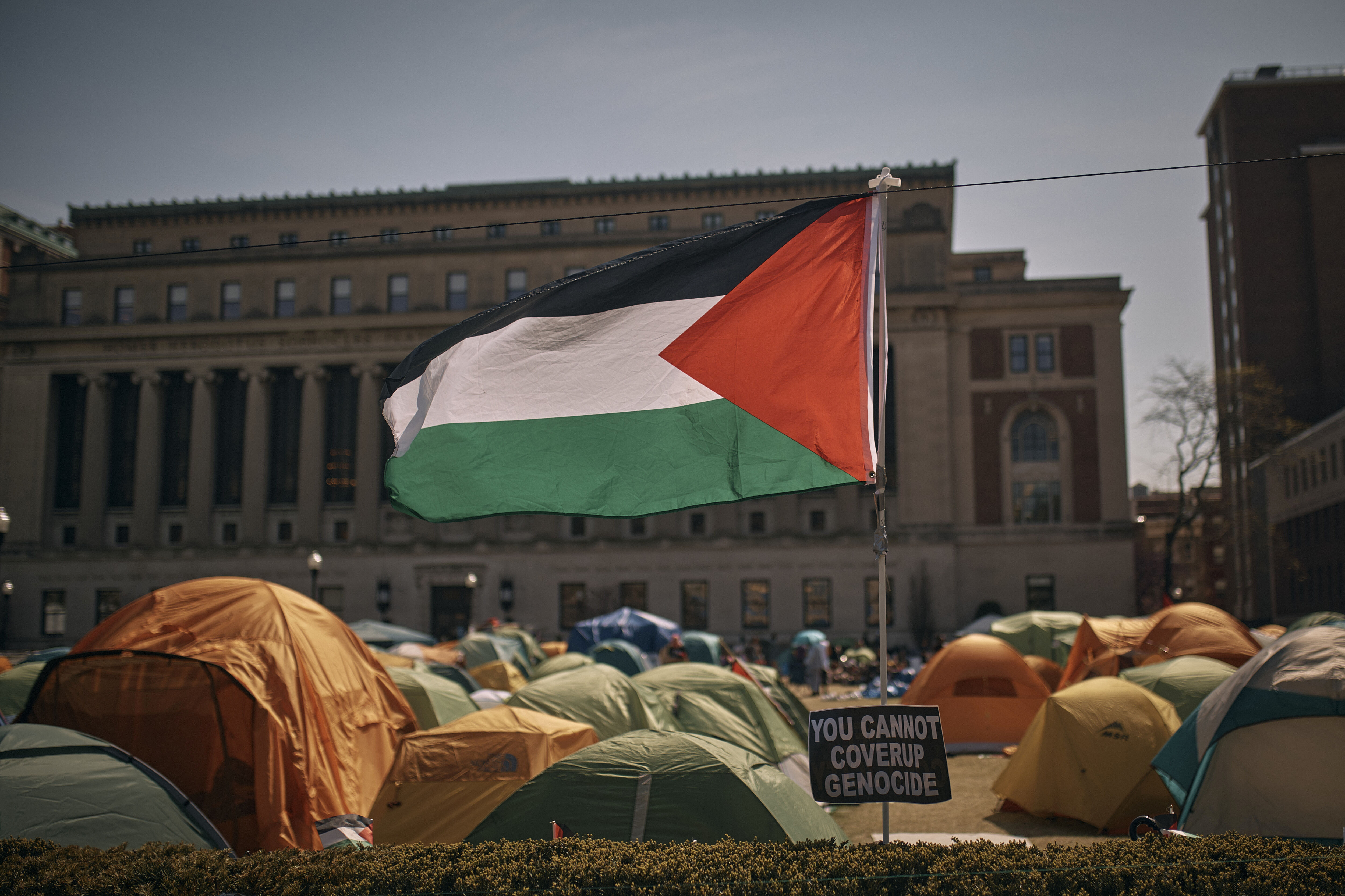 a Palestinian flag can be see next to tents and a stately building
