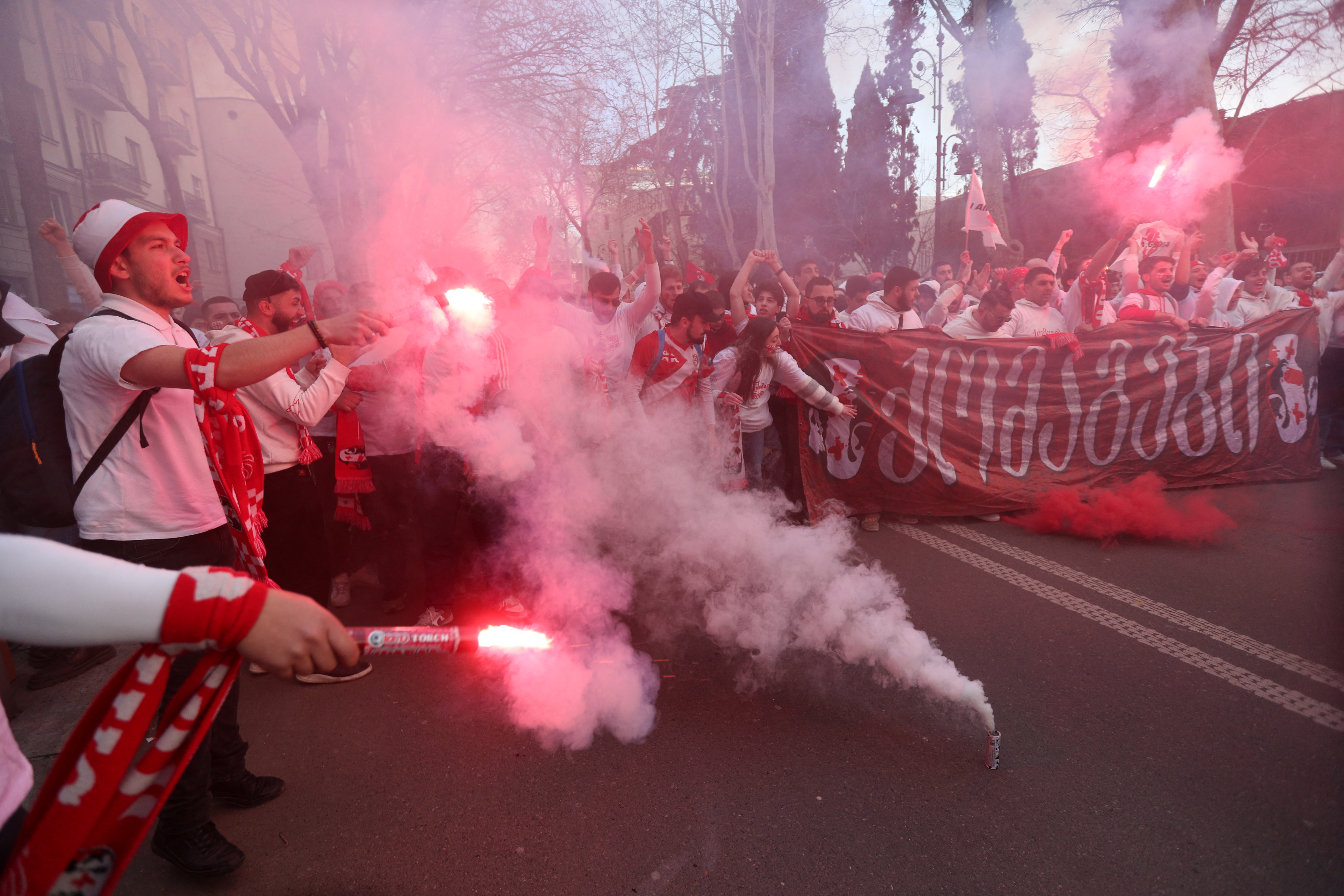 Football fans holding flares and banners.