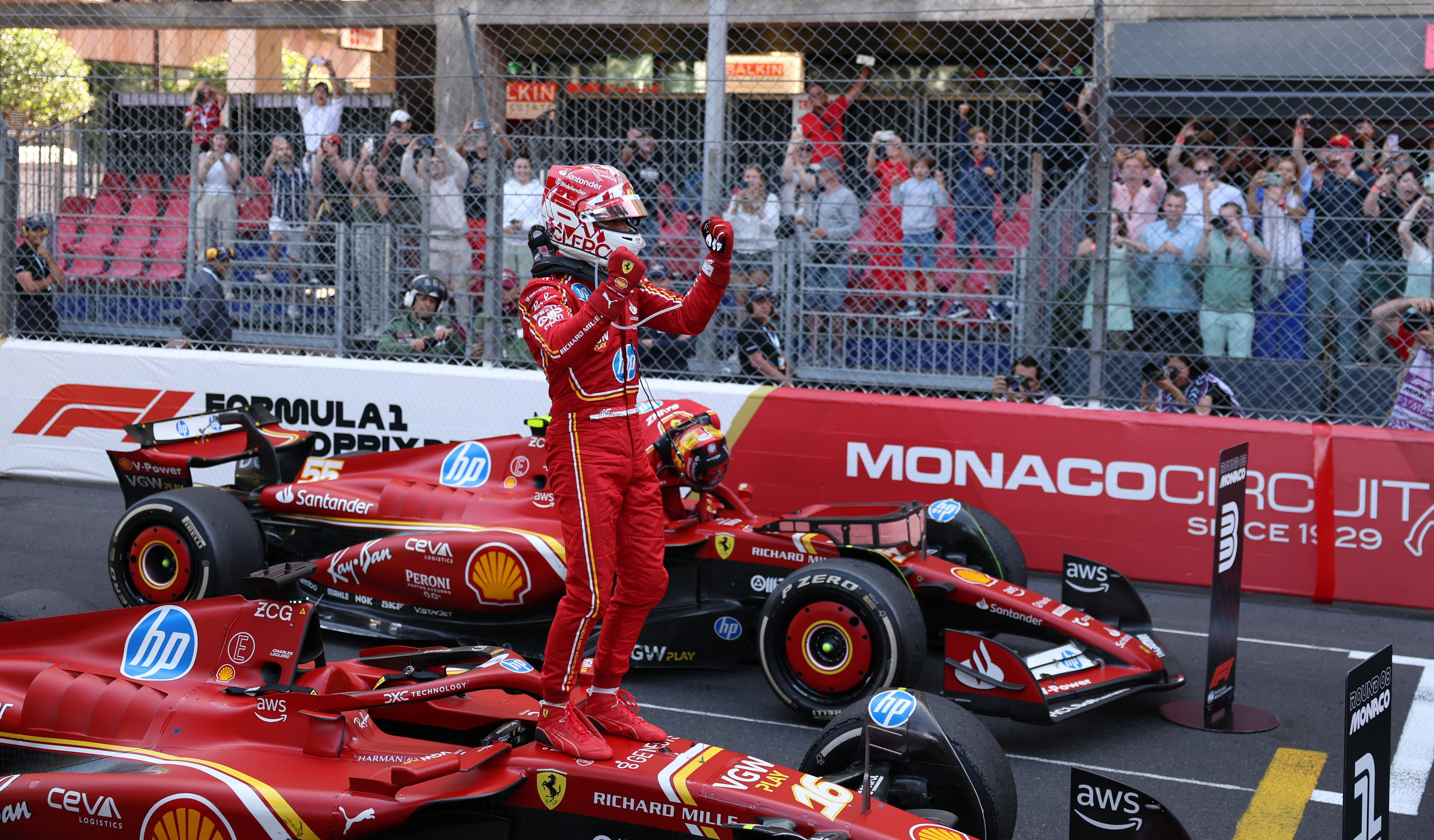 driver stands on race car and celebrates.