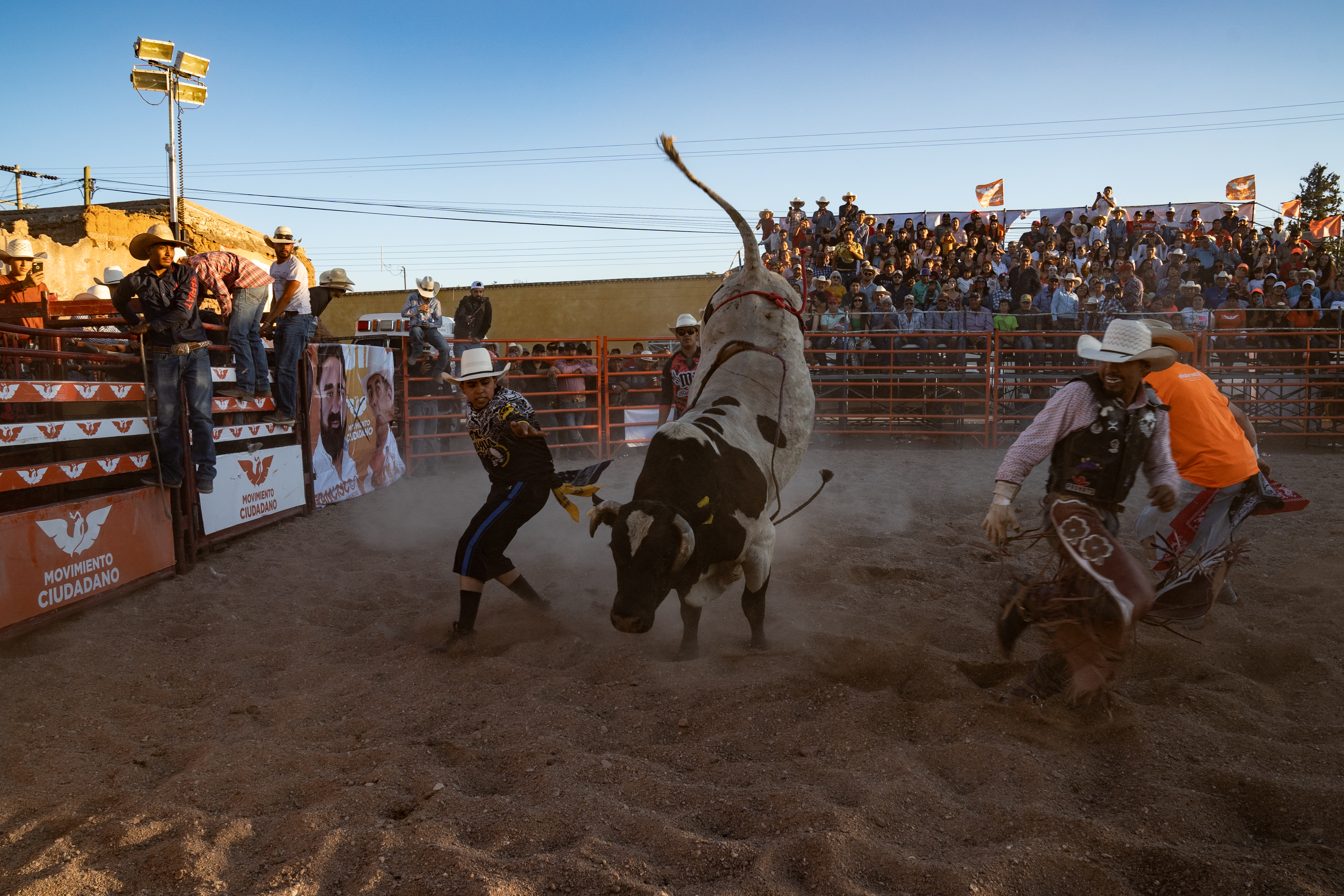 A bullfighter tangles with a bucking bull in a rodeo ring.