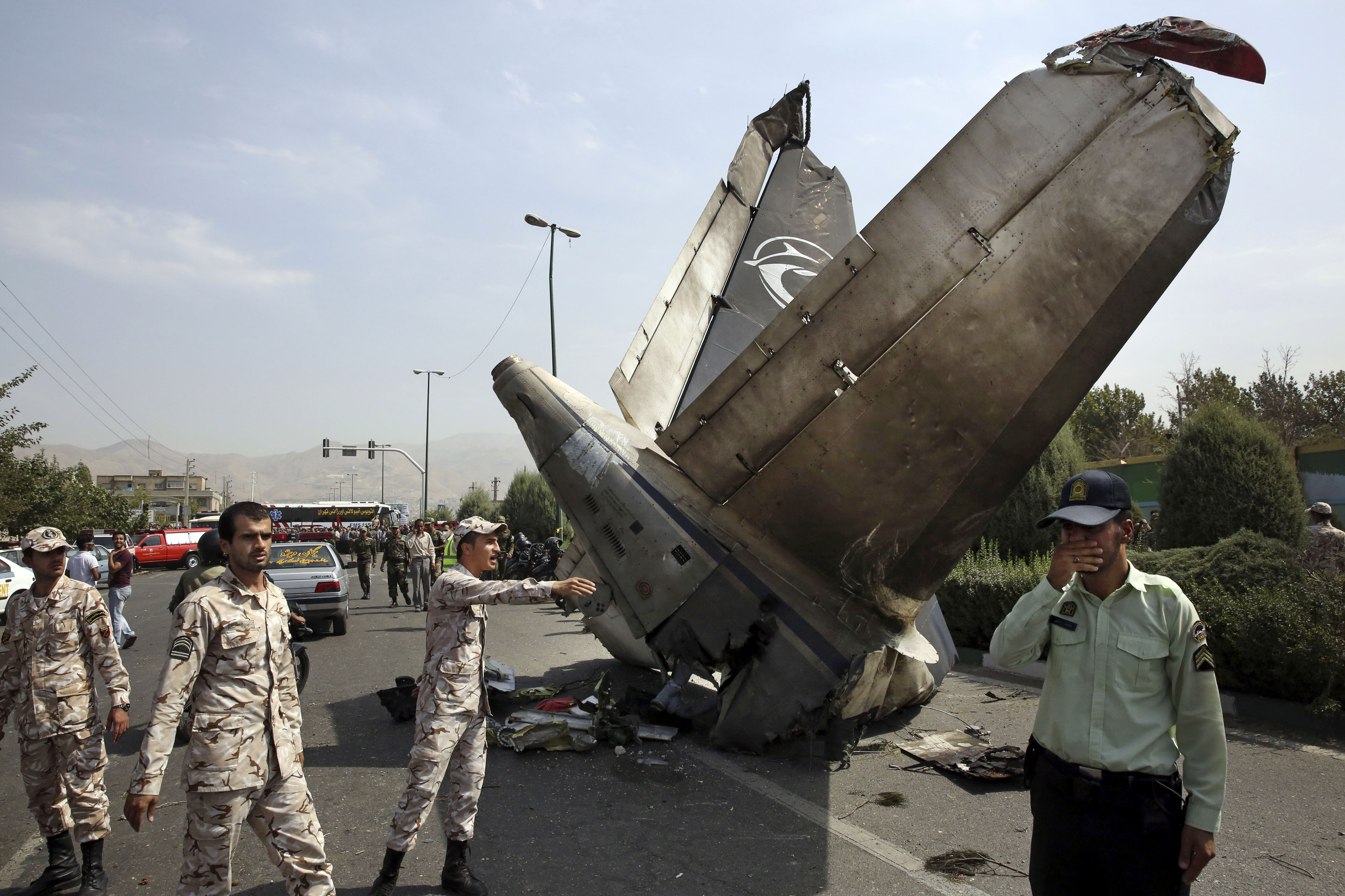 Iranian Revolutionary Guards and police officers inspect the site of a passenger plane crash near the capital Tehran, Iran, Sunday, Aug. 10, 2014.