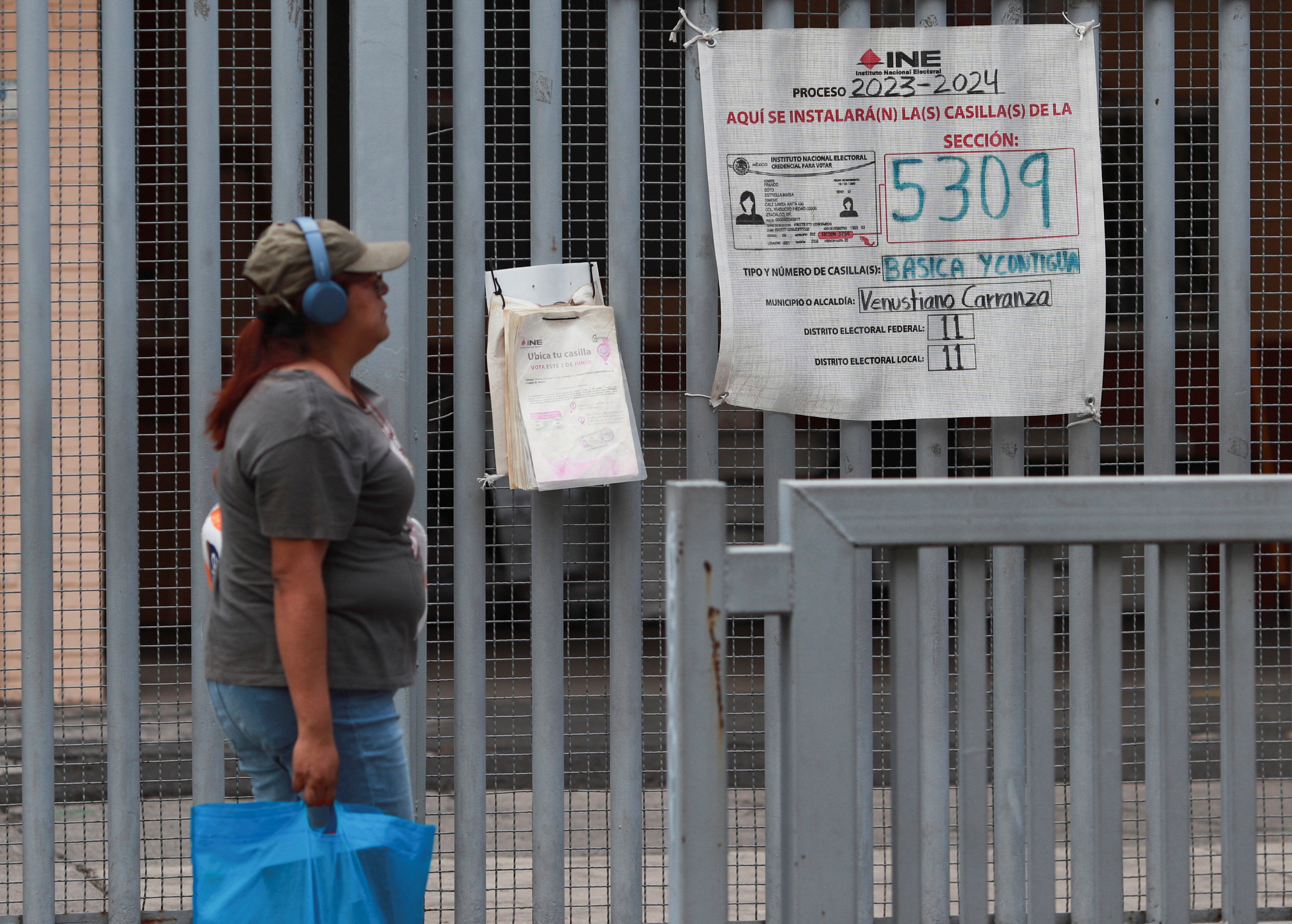 A woman walks past a sign for a polling station.