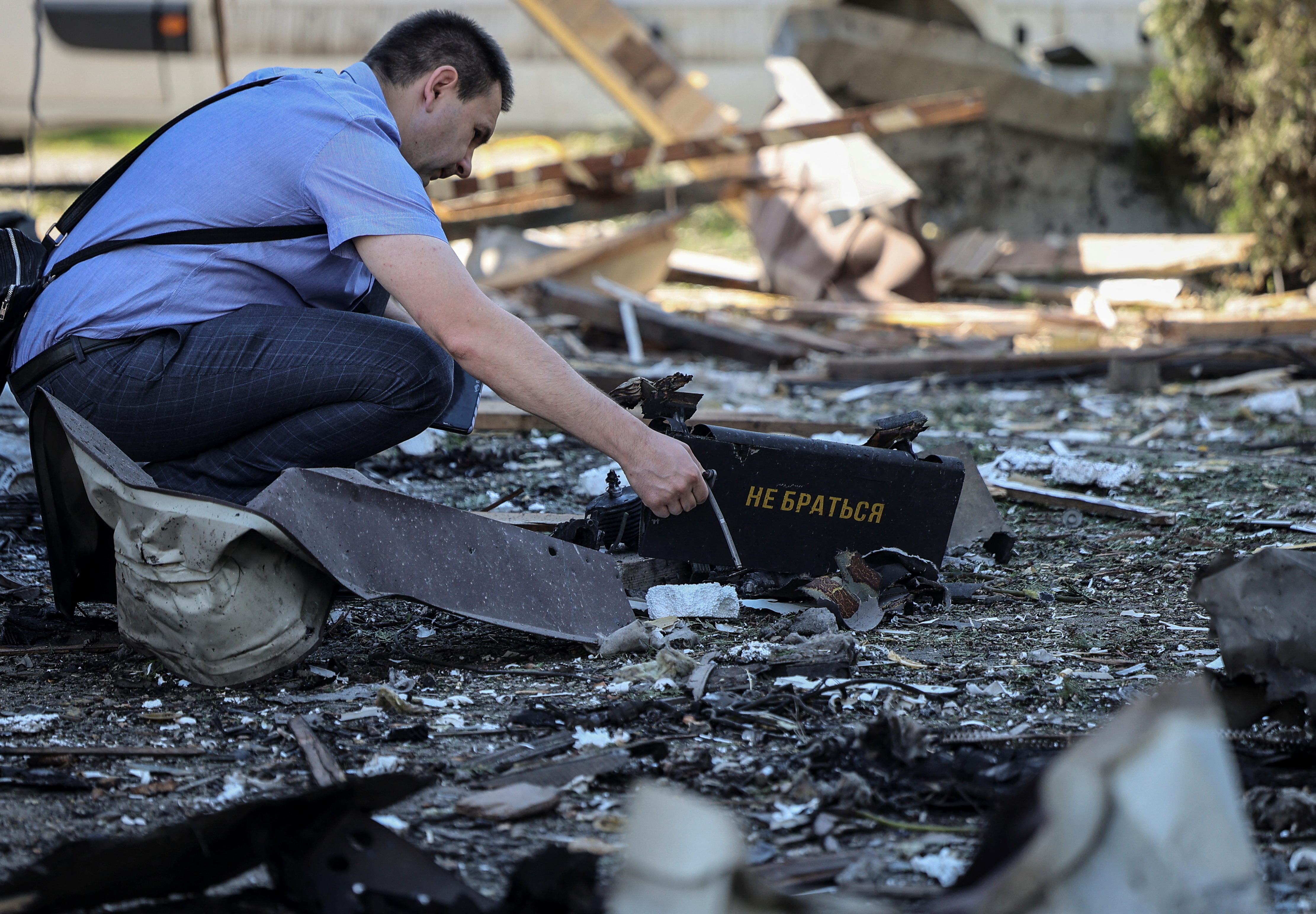 A war crimes prosecutor works at the site of a Russian drone attack on the outskirts of Lviv in western Ukraine on June 19, 2024 [Roman Baluk/Reuters]