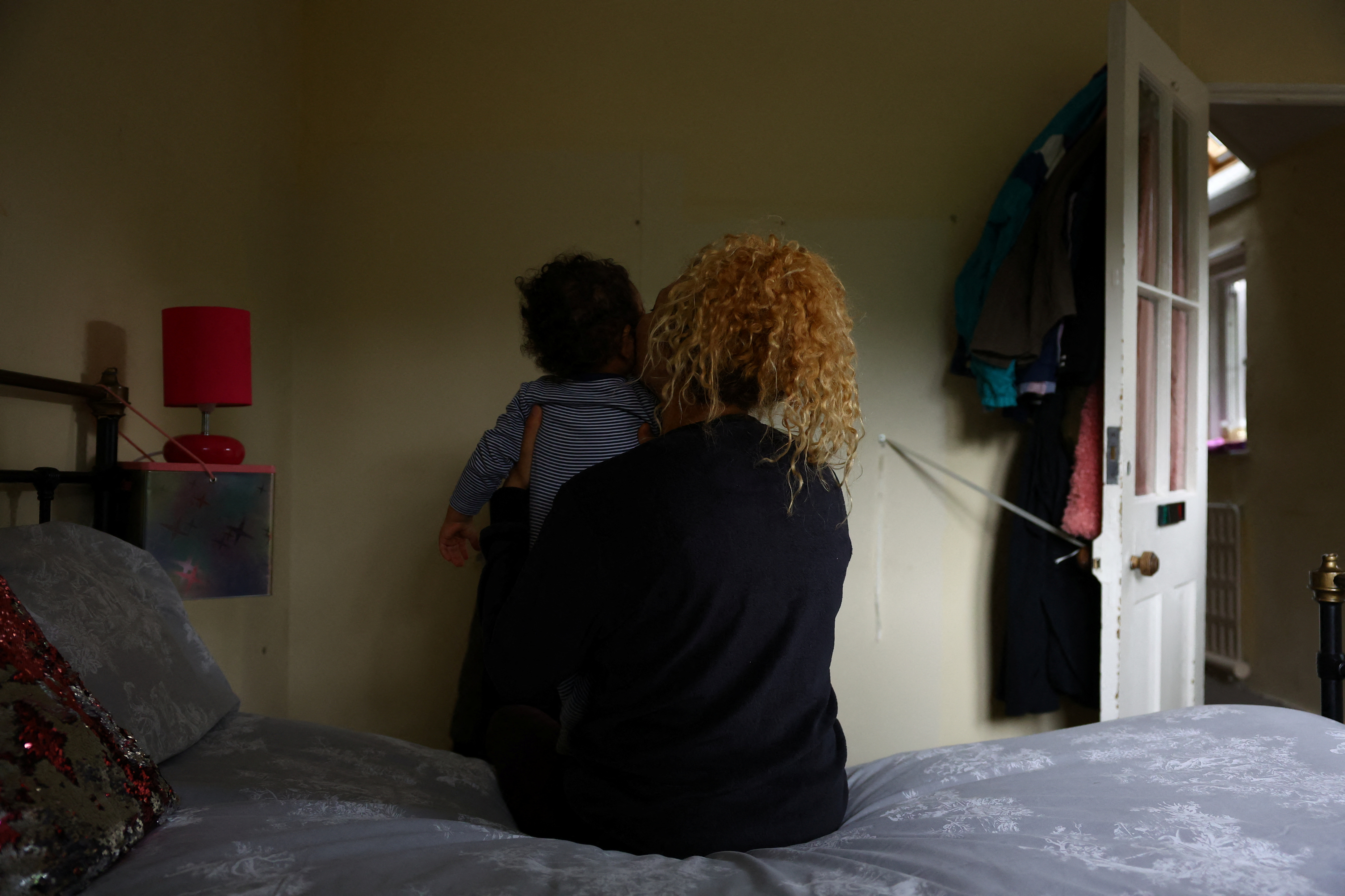 Oumnia, 35, holds her baby as she sits on her bed in a former school that is now occupied by squatter activist group Reclaim Croydon, in Croydon, south London, Britain, June 13