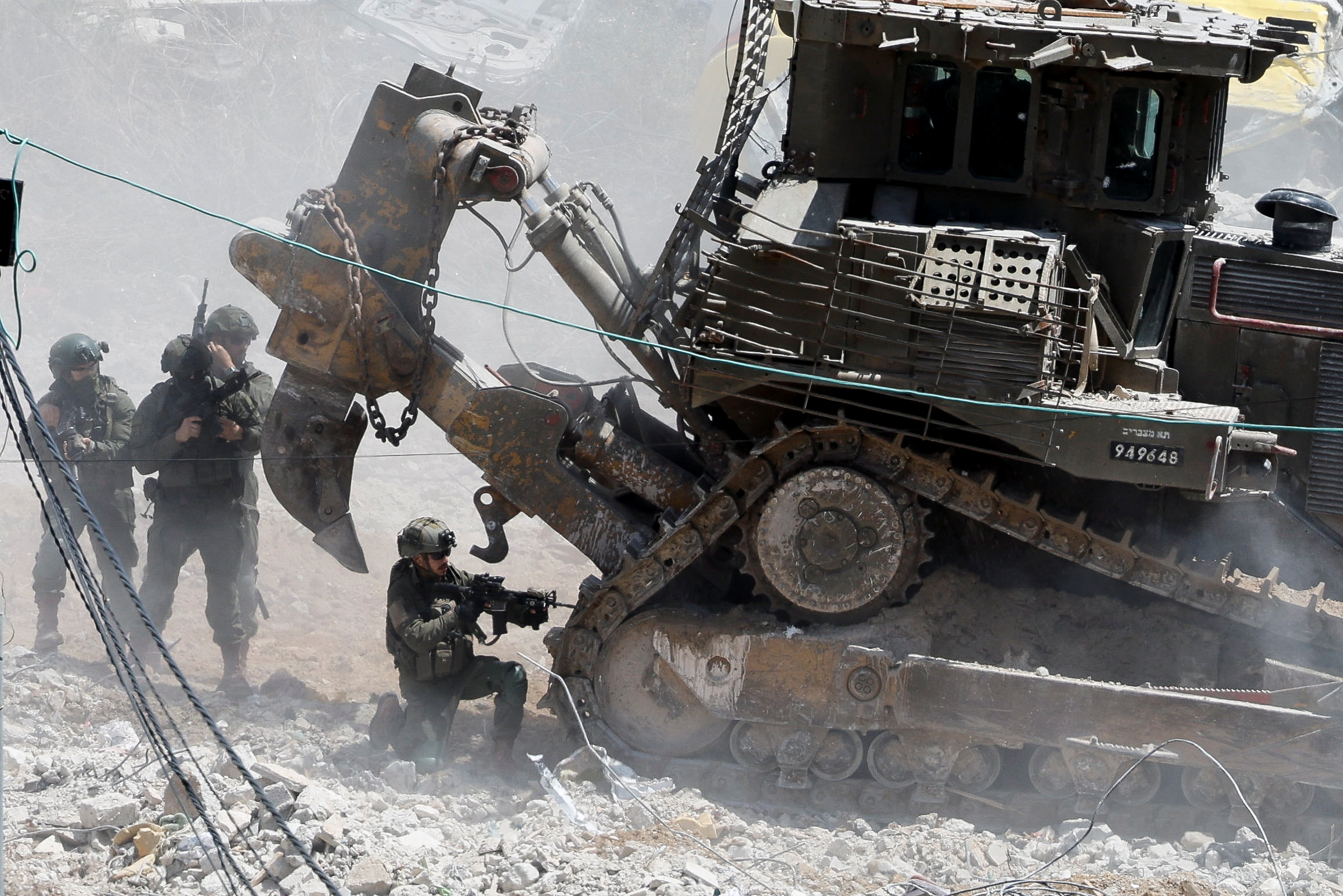 soldiers fire from next to an armoured bulldozer