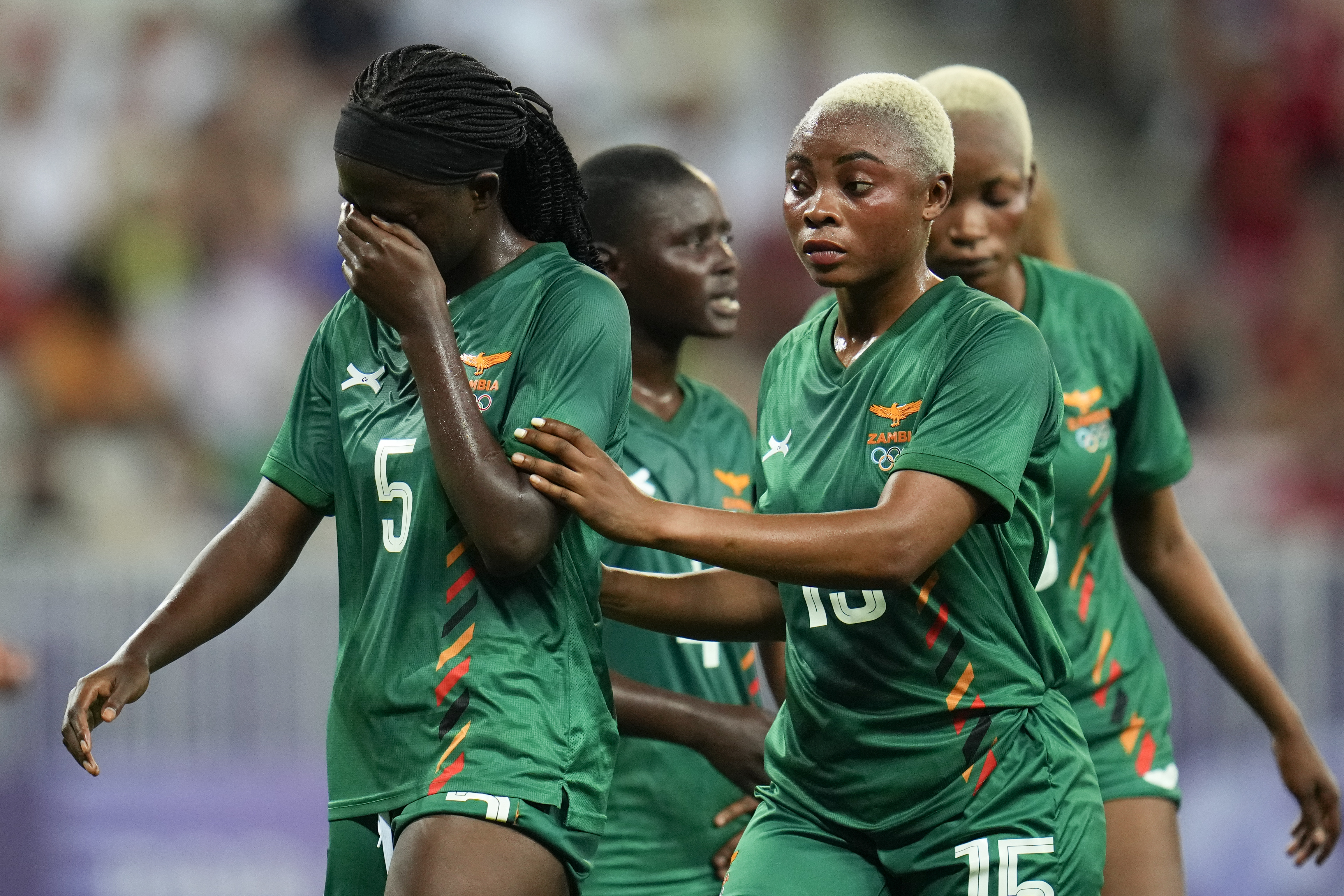 Zambia's Pauline Zulu, left, walks with teammate Hellen Chanda after she was given a red card by referee Ramon Abatti, of Brazil, during a women's group B match between the United States and Zambia at Nice Stadium at the 2024 Summer Olympics, Thursday, July 25, 2024, in Nice, France. (AP Photo/Julio Cortez)