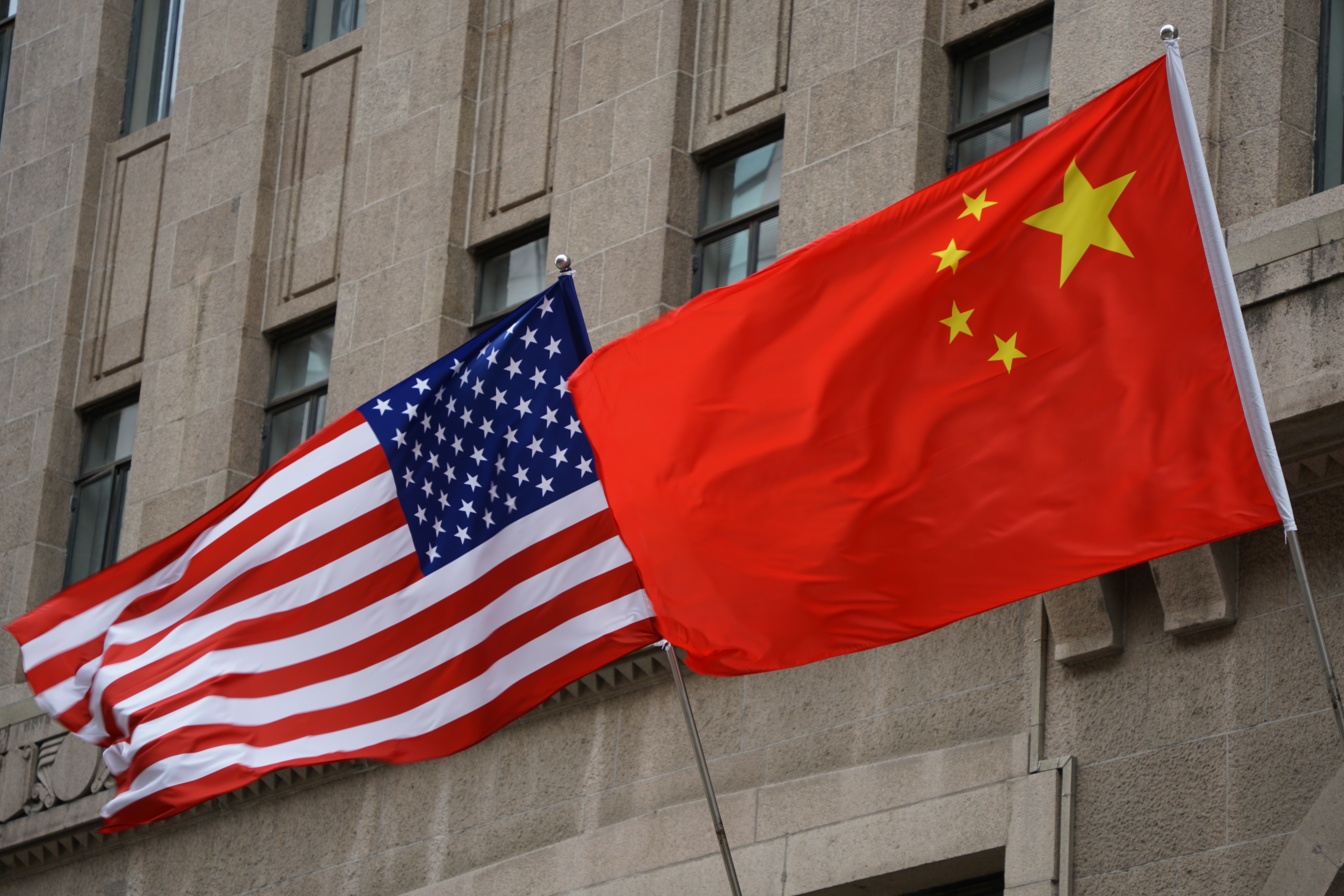 The national flags of the United States and China flutter at the Fairmont Peace Hotel in Shanghai, China