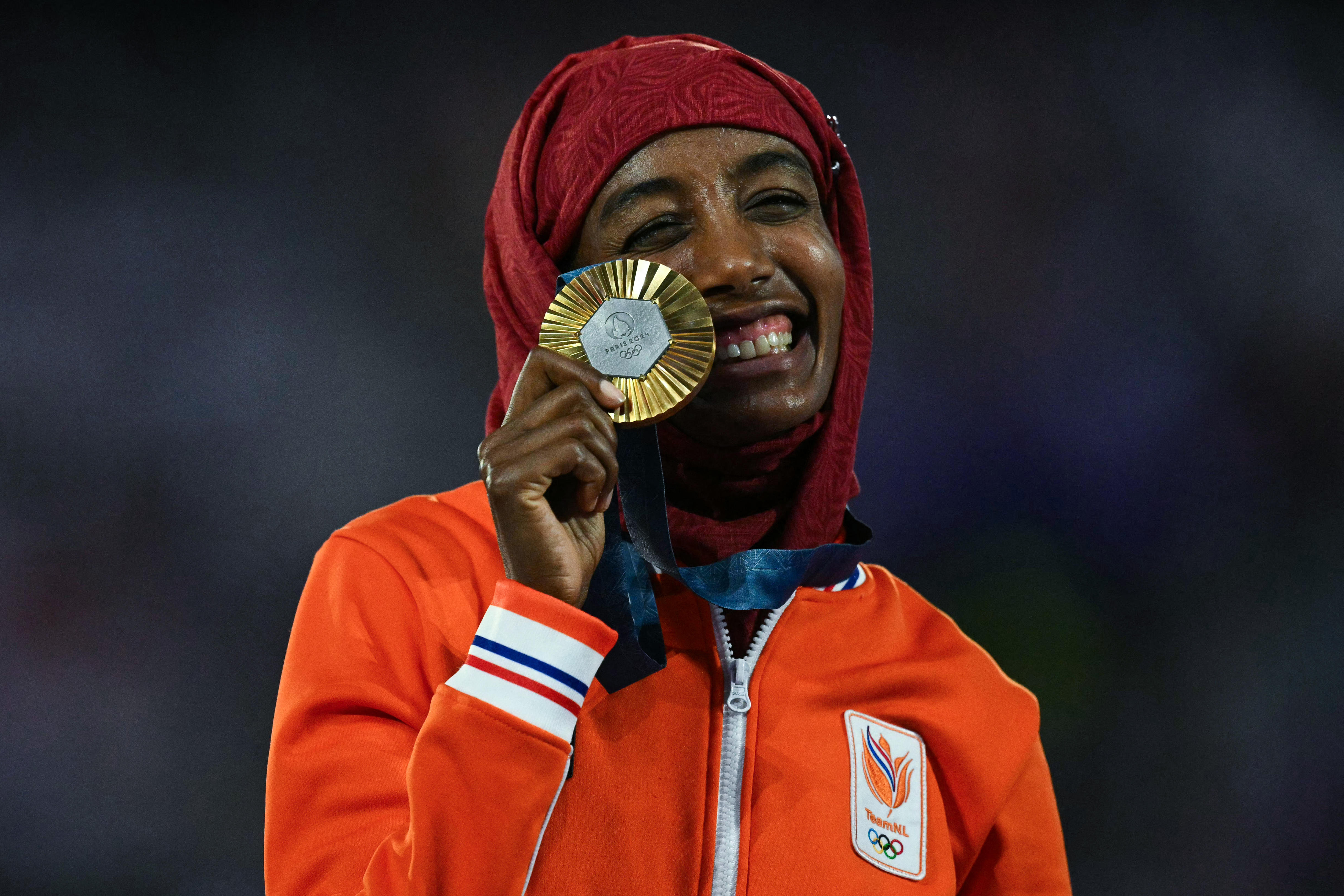 Hijab-clad distance runner Sifan Hassan of the Netherlands shows off her gold medal during the closing ceremony of the Paris 2024 Olympic Games at the Stade de France, in Saint-Denis, in the outskirts of Paris [Oli Scarff/AFP]