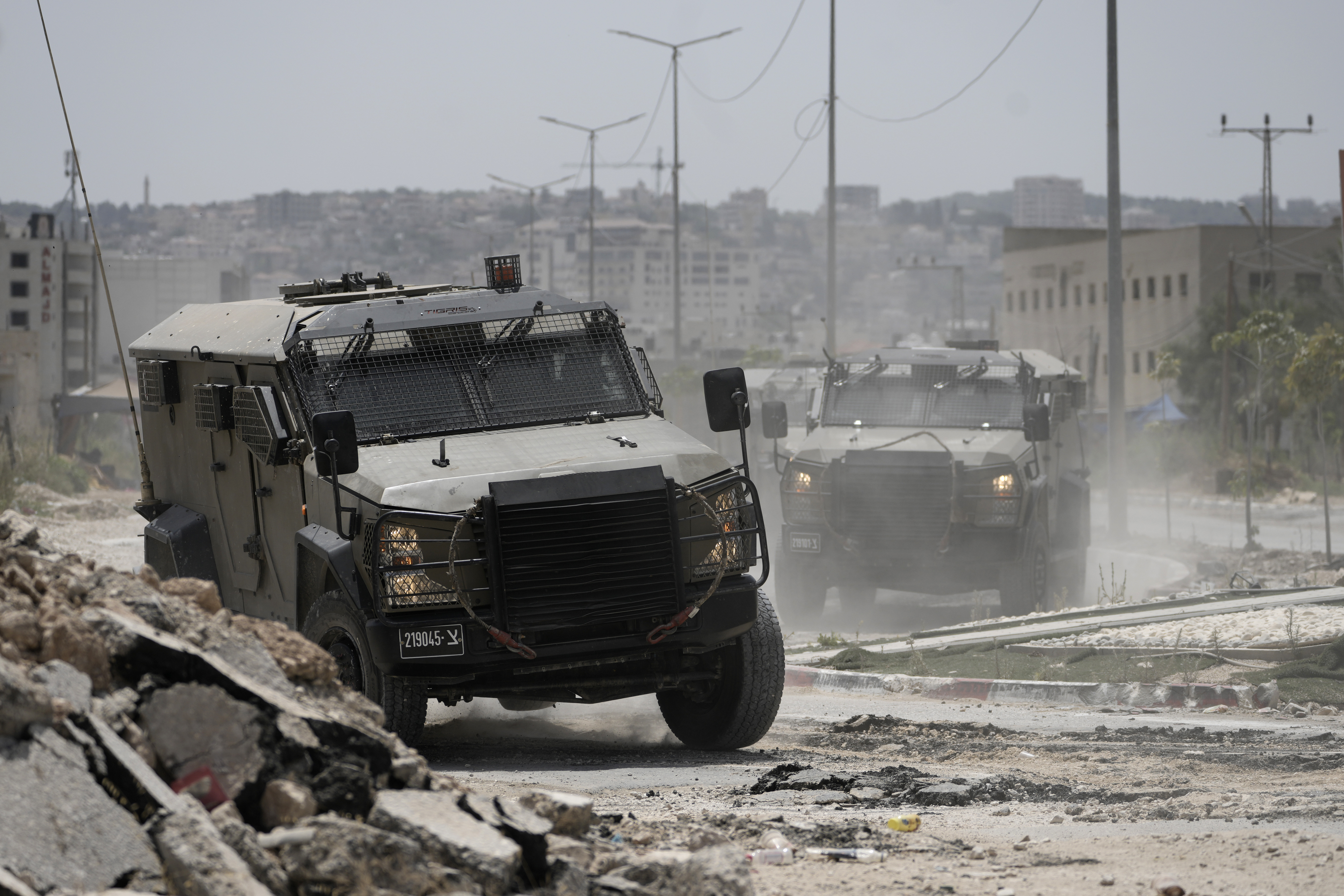 two military vehicles drive on a destroyed road