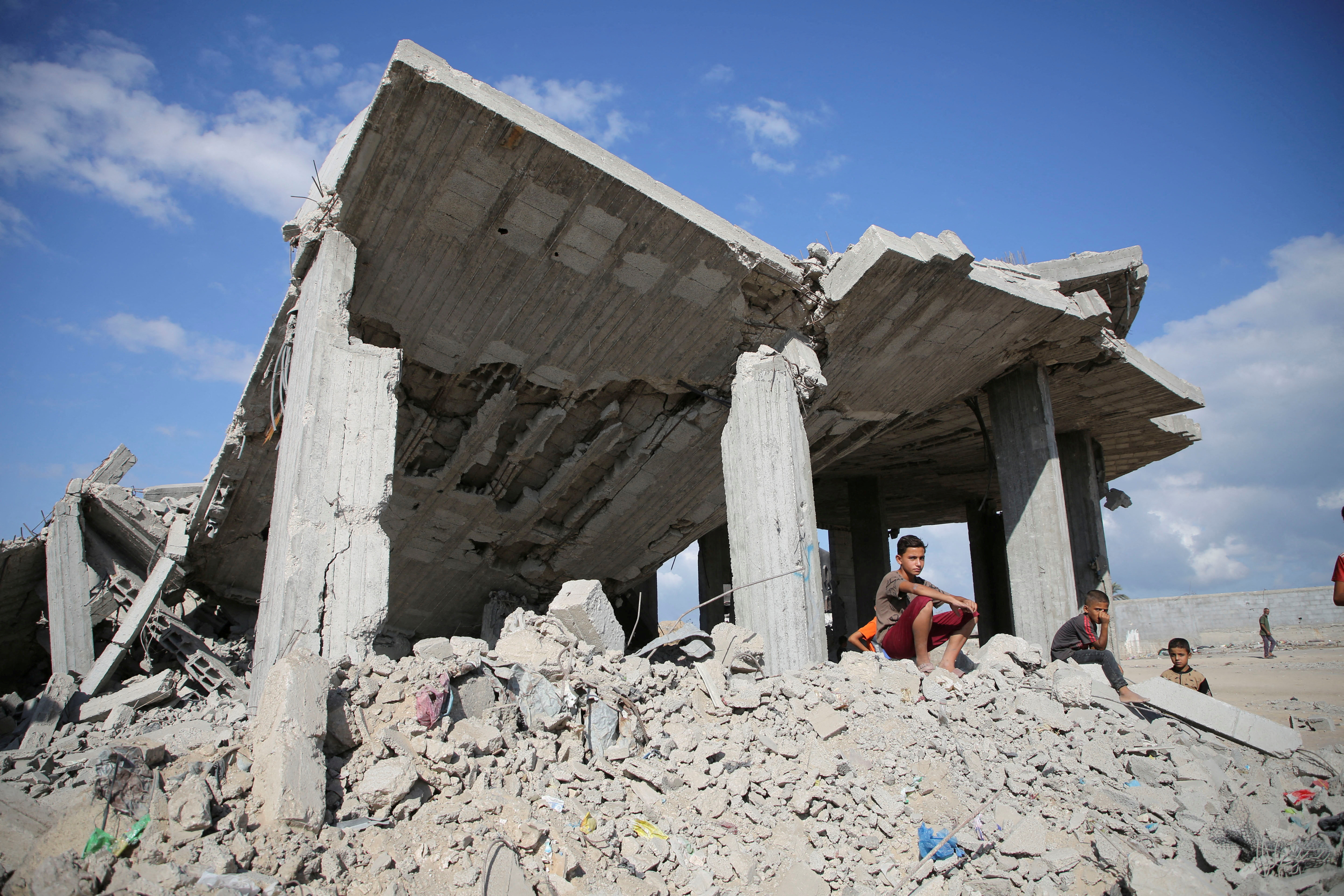 Palestinian boys sit on piles of debris after Israeli strikes on houses, in Khan Younis, southern Gaza Strip [File: Hatem Khaled/Reuters]