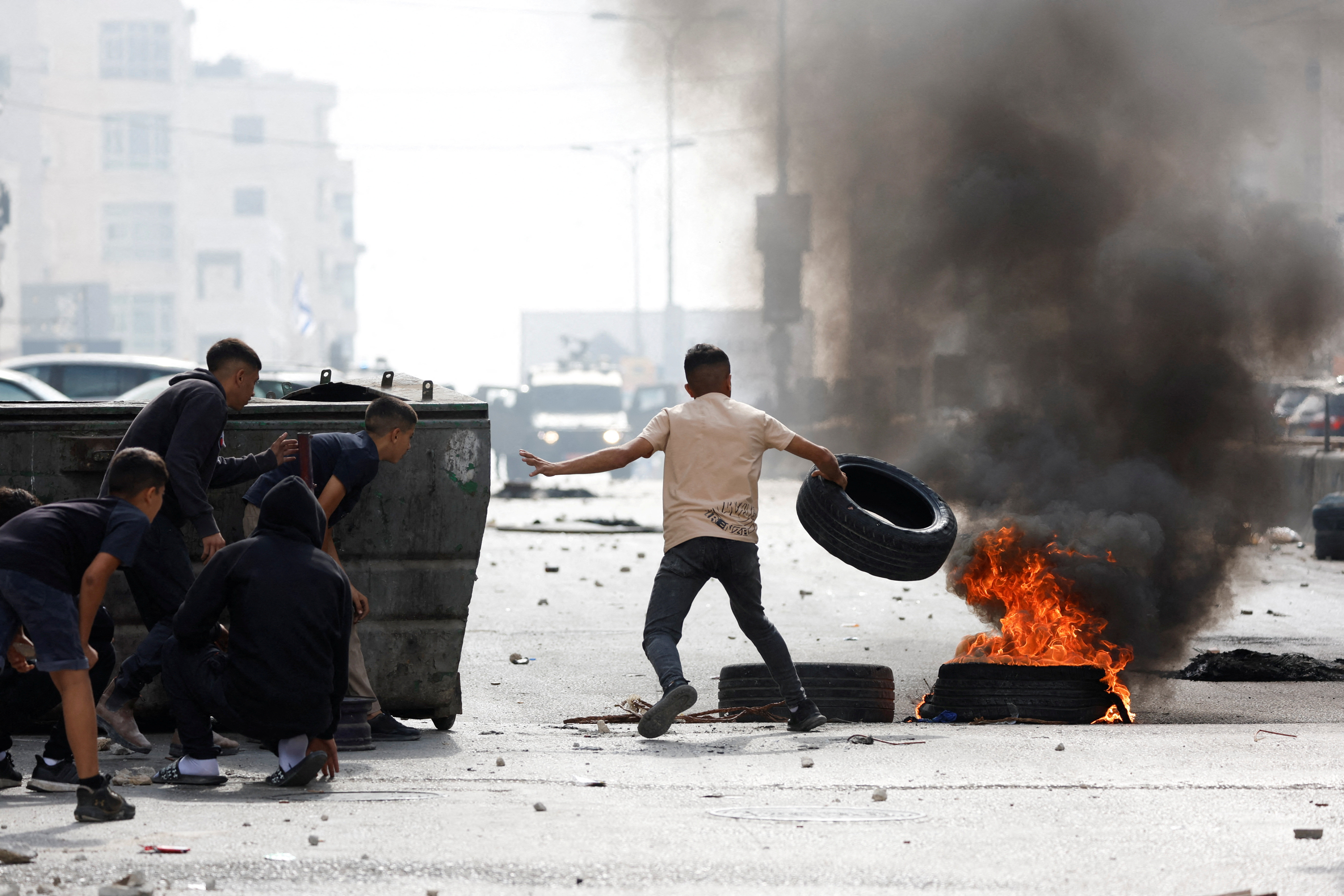 A Palestinian boy throws a tire on a fire during an Israeli raid in Qalandya, in the Israeli-occupied West Bank, October 7