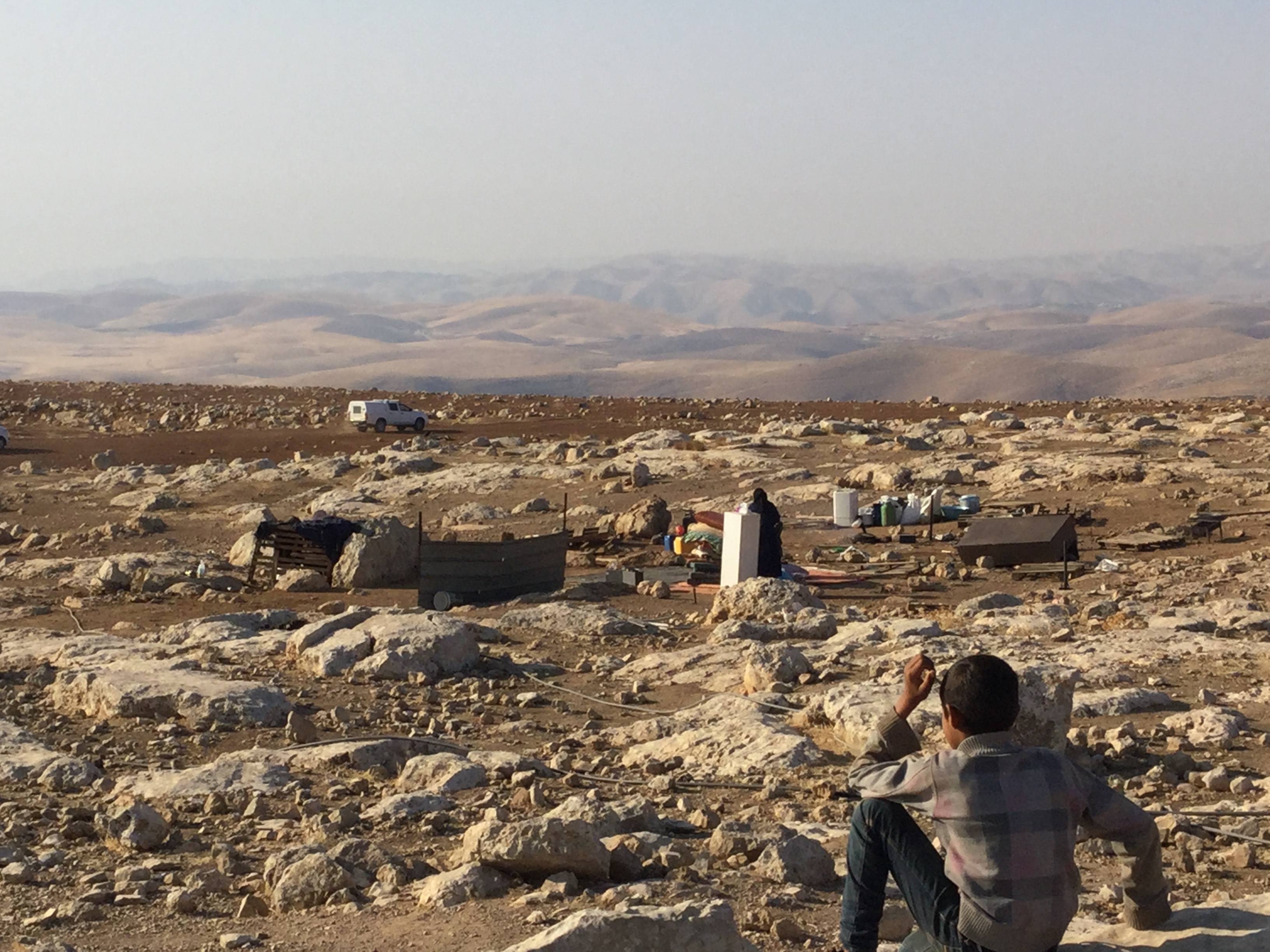 Child looks on at tents in an open landscape