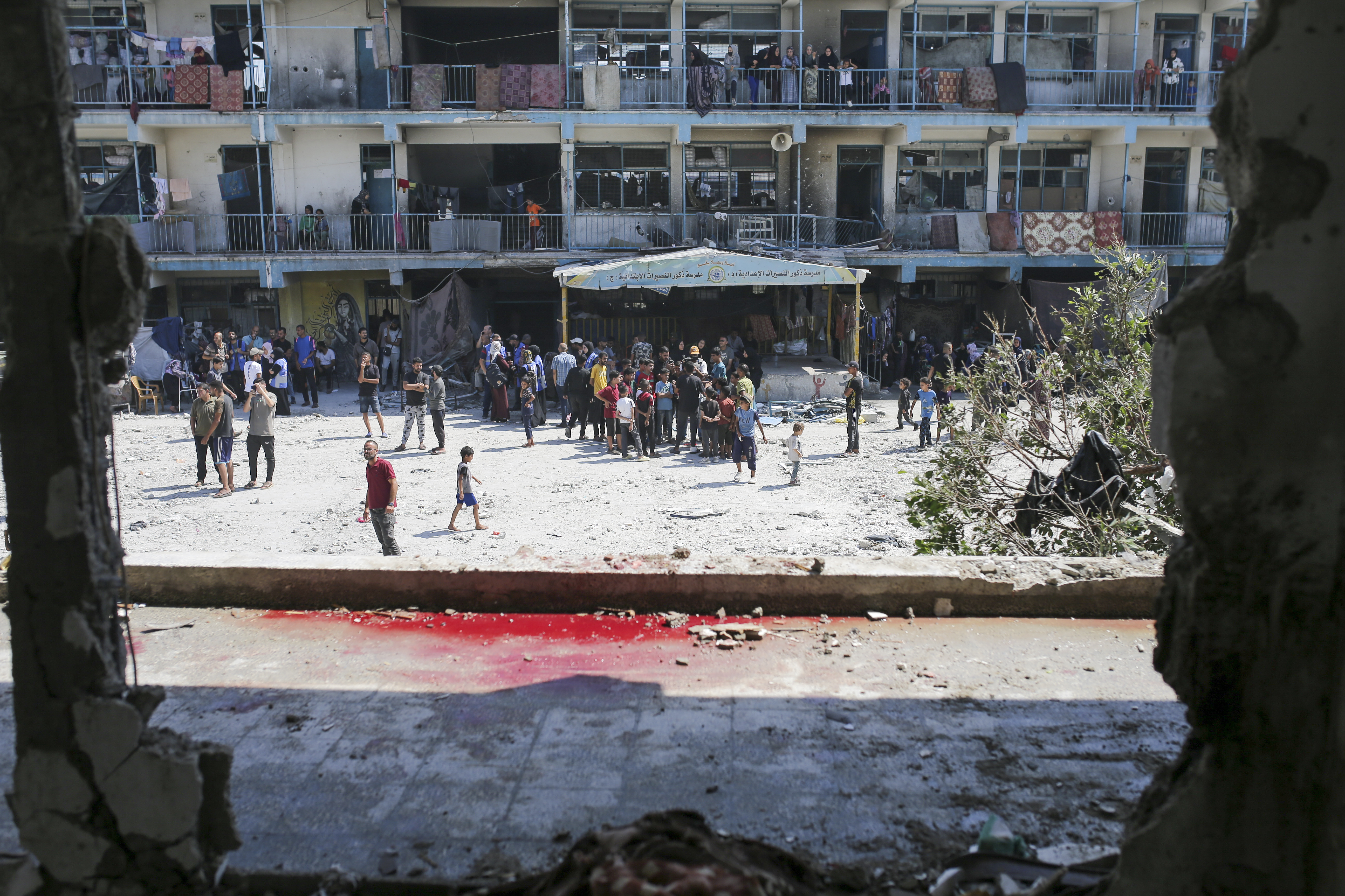 Palestinians look at the aftermath of the Israeli strike on a U.N.-run school