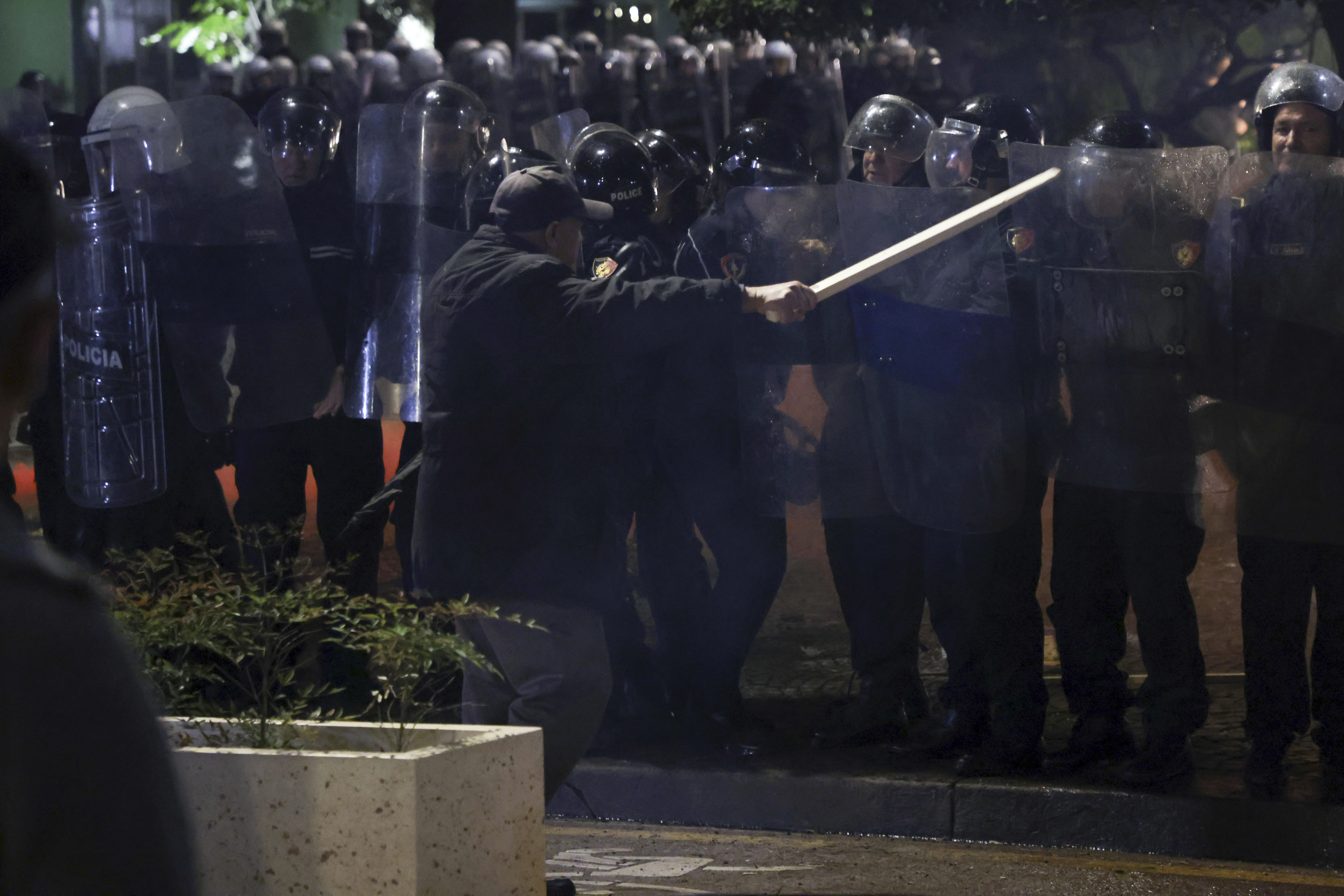 An opposition supporter waves a wooden stick to riot police during a anti-government rally, in Tirana, Albania, Monday, Oct. 7