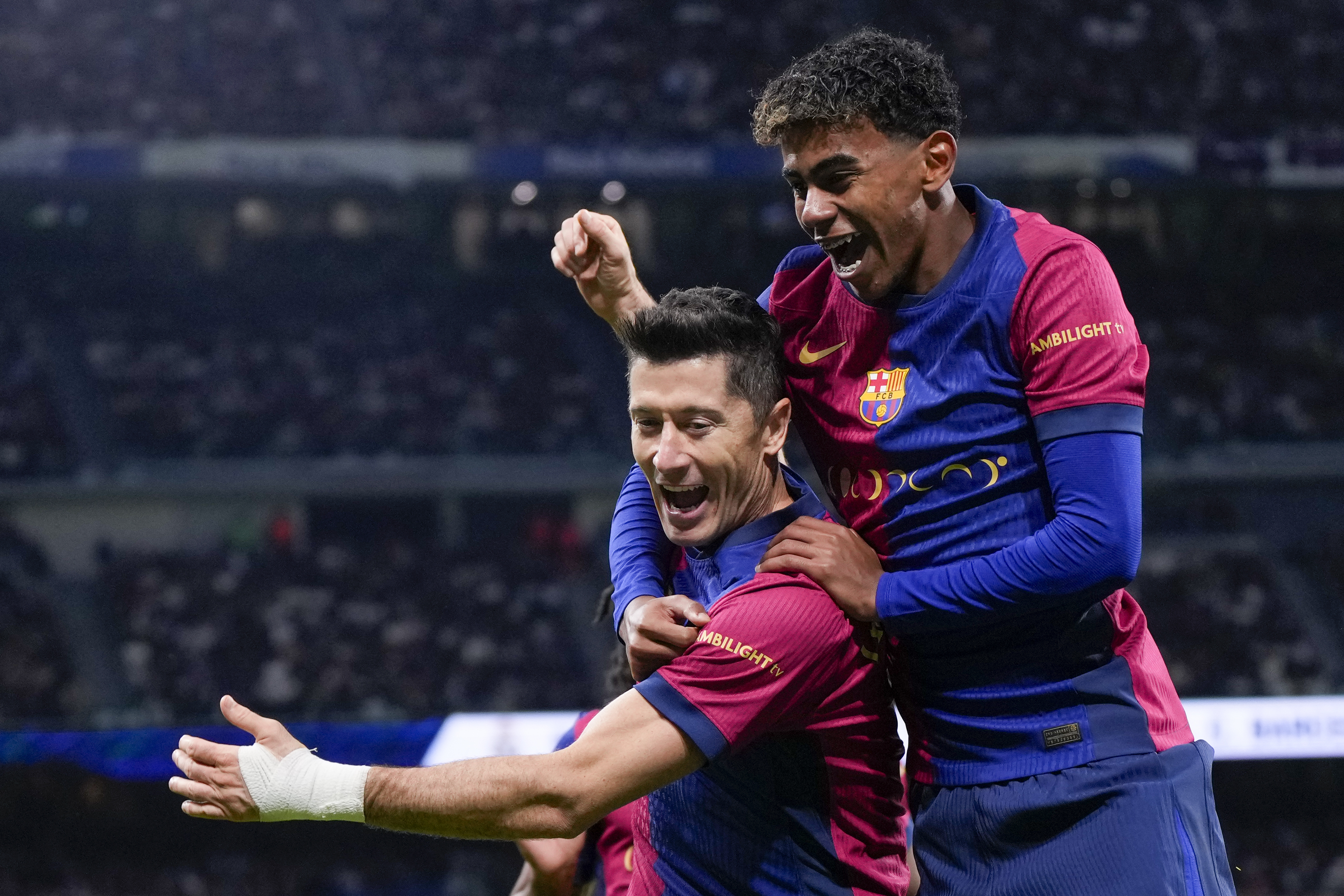 Barcelona's Robert Lewandowski celebrates after scoring his side's second goal with Barcelona's Lamine Yamal, right, during a Spanish La Liga soccer match between Real Madrid and Barcelona at the Santiago Bernabeu stadium in Madrid, Spain, Saturday, Oct. 26, 2024. (AP Photo/Manu Fernandez)