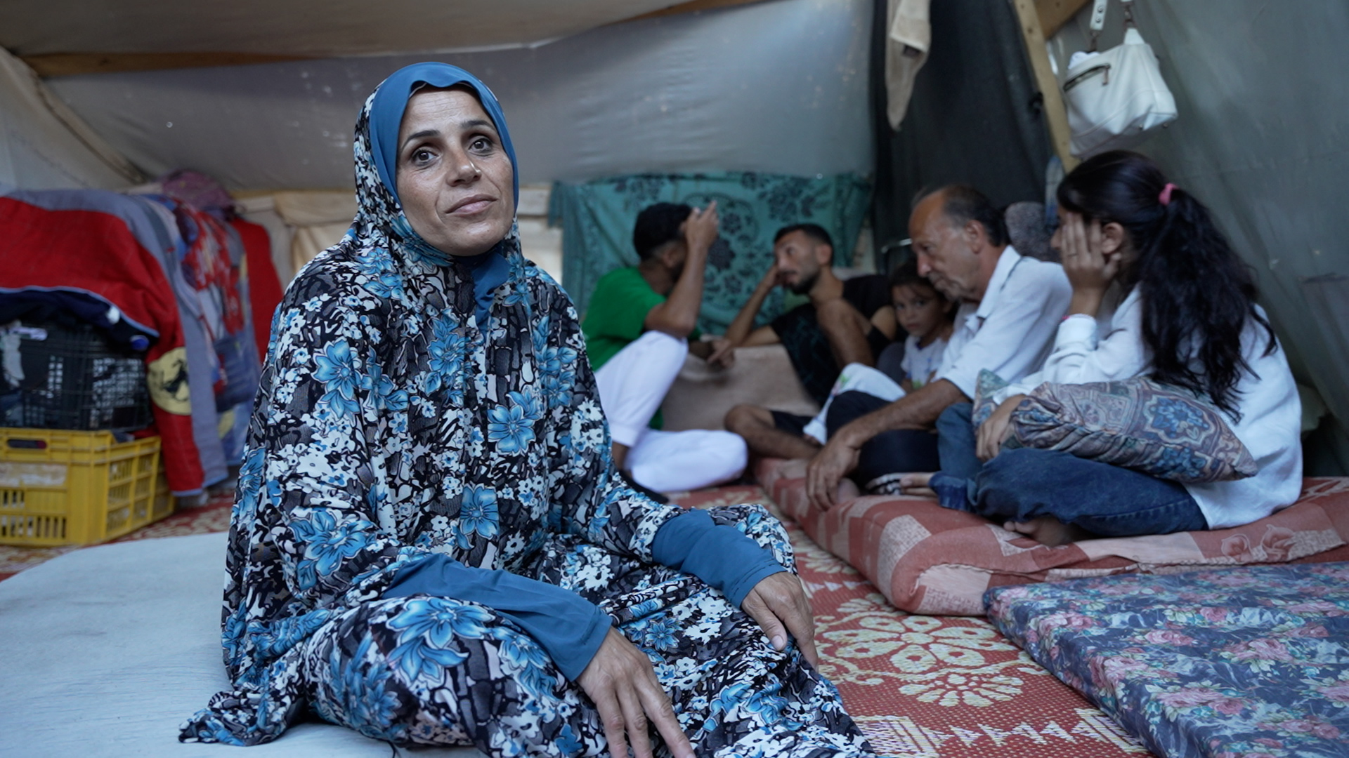 Image of Palestinian woman, Sabreen Lushan with her family, who have been displaced 14 times in Gaza. (Al Jazeera)