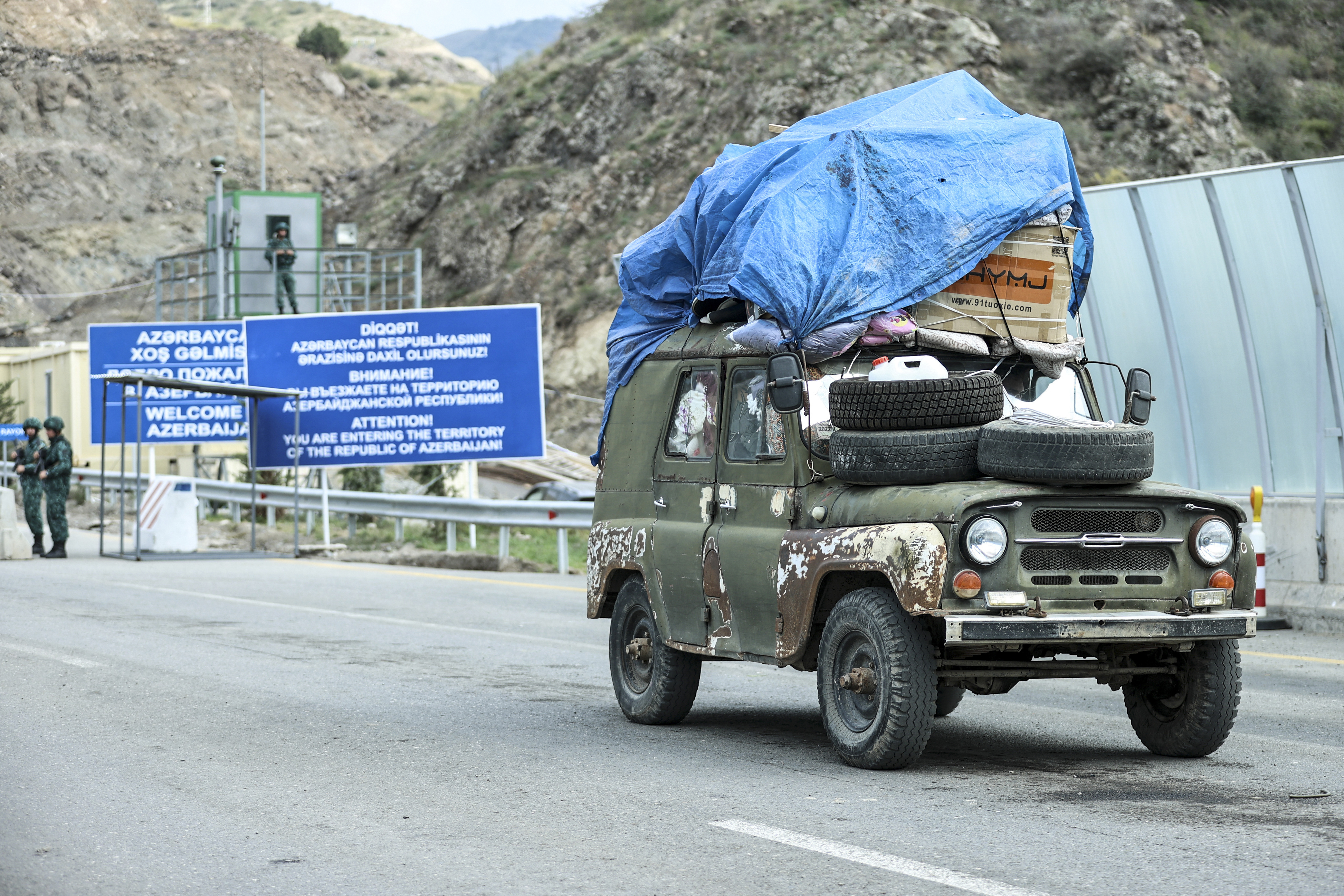 An ethnic Armenian resident of Nagorno-Karabakh, drives his Soviet-made vehicle past Azerbaijani border guard servicemen after been checked at the Lachin checkpoint on the way from Nagorno-Karabakh to Armenia, in Azerbaijan, Sunday, Oct. 1, 2023. [AP Photo/Aziz Karimov/File]
