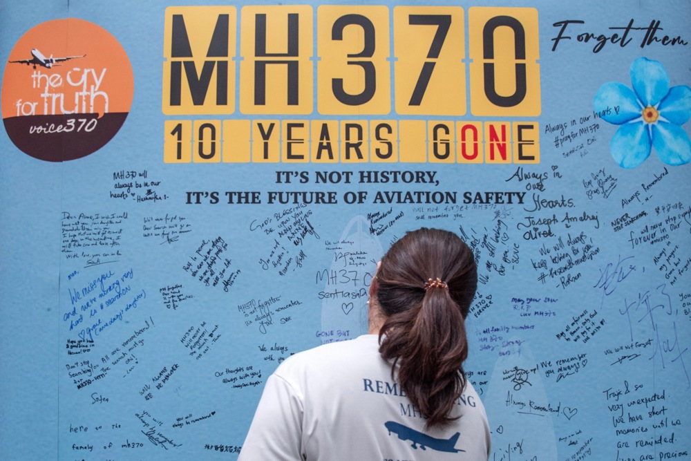 A family member of a passenger of the missing Malaysian Airlines flight MH370 writes on a memorial wall during a remembrance event marking the 10th anniversary of its disappearance at the Empire Subang in Subang Jaya, Selangor, Malaysia, in 2024