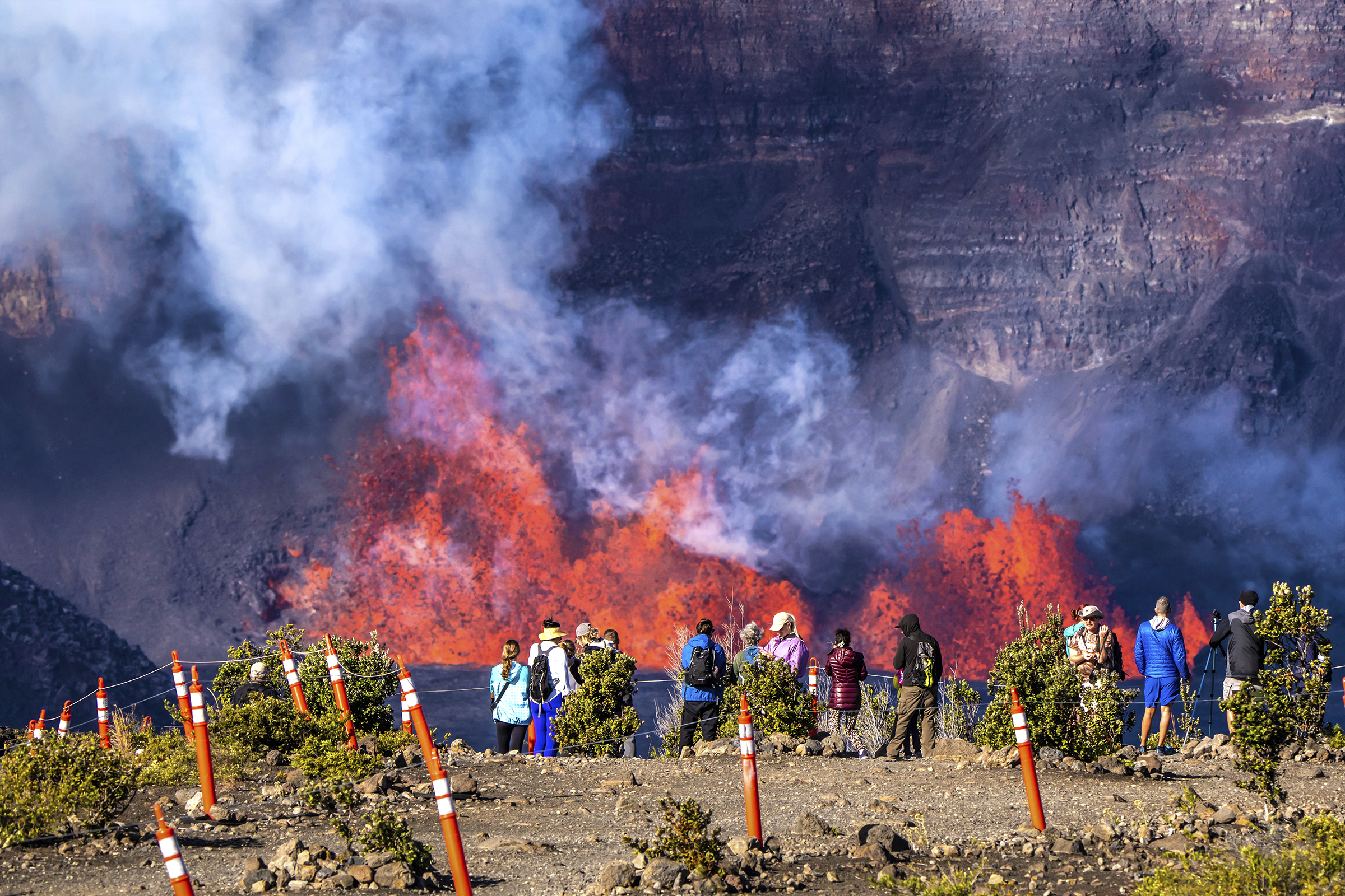 People look on as lava shoots out during an eruption of the Kilauea volcano on Hawaii