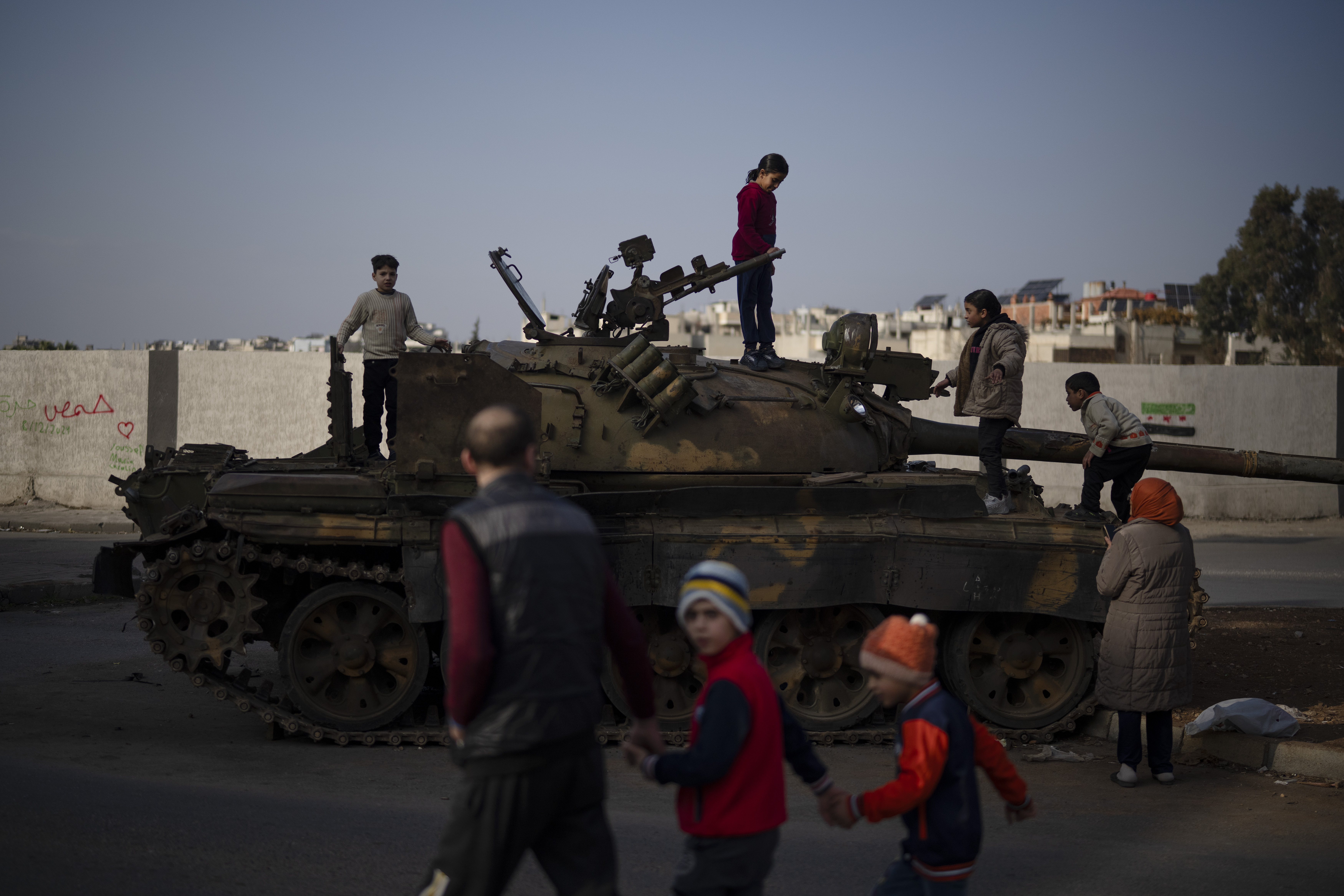 Children on the top of an ousted Syrian government forces tank that was left on a street in an Alawite neighbourhood, in Homs, Syria, Thursday, Dec. 26