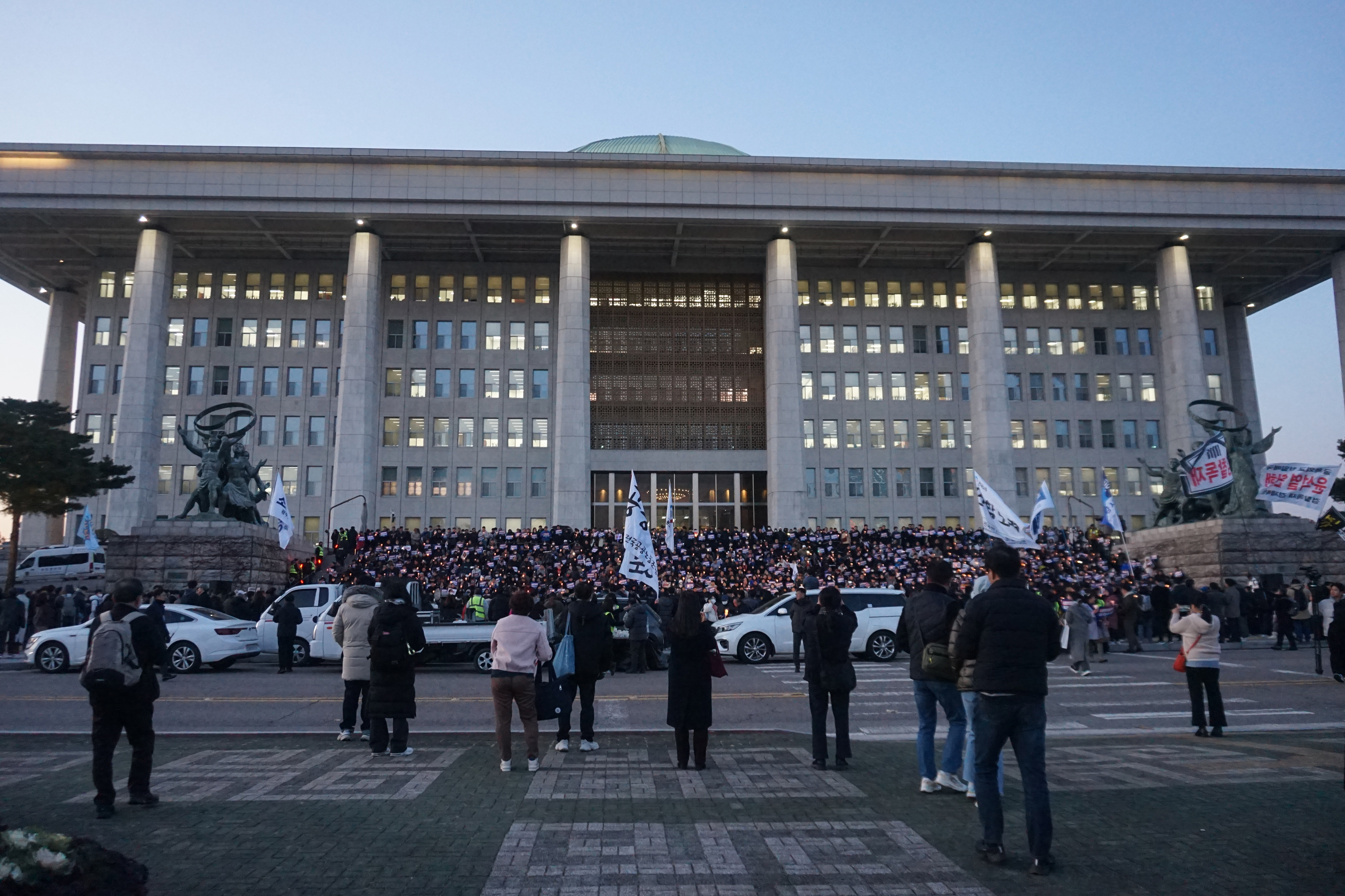 Demonstraters fill up the main stairways of the National Assembly building with posters reading 'Impeach Yoon Seok Yeol'