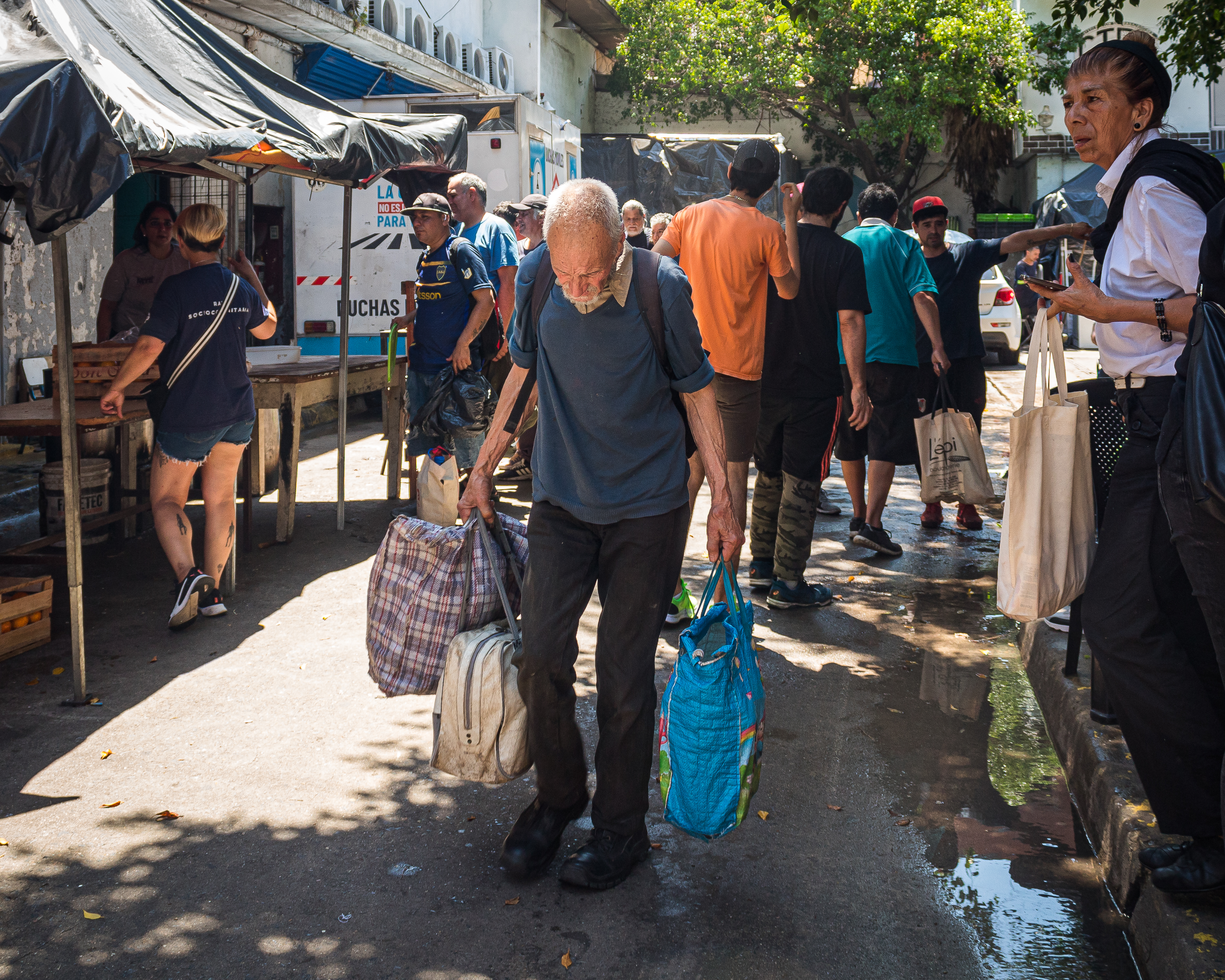 A man leaves a soup kitchen in Buenos Aires with tote bags full of food