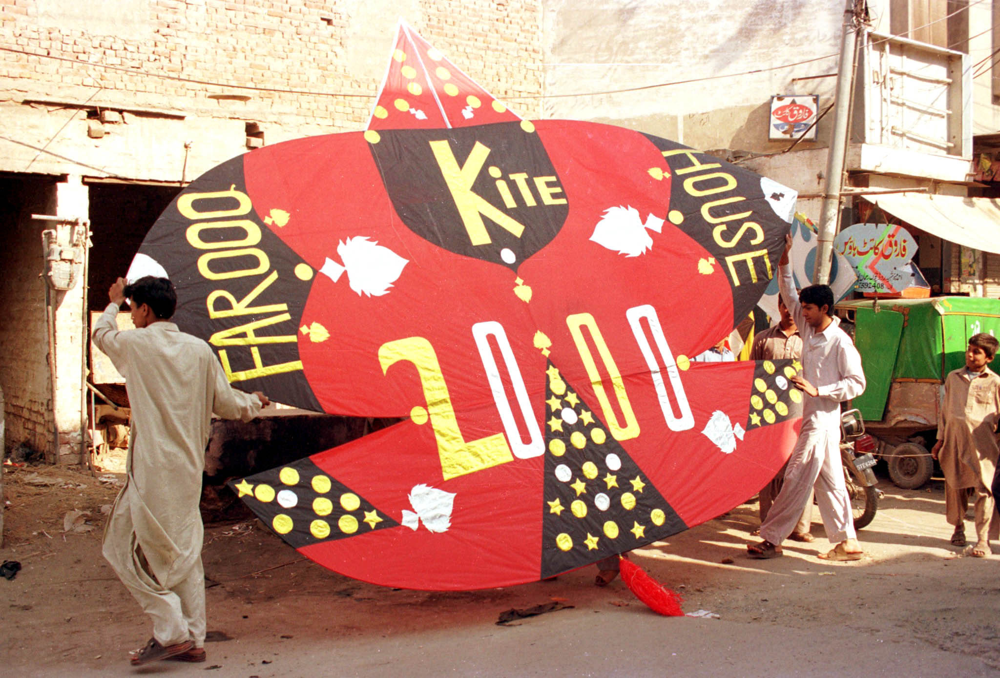 Two Pakistani youths carry a giant paper kite with &#039;Kite 2000&#039; written on it, on the eve of Basant in Lahore [File: Reuters]