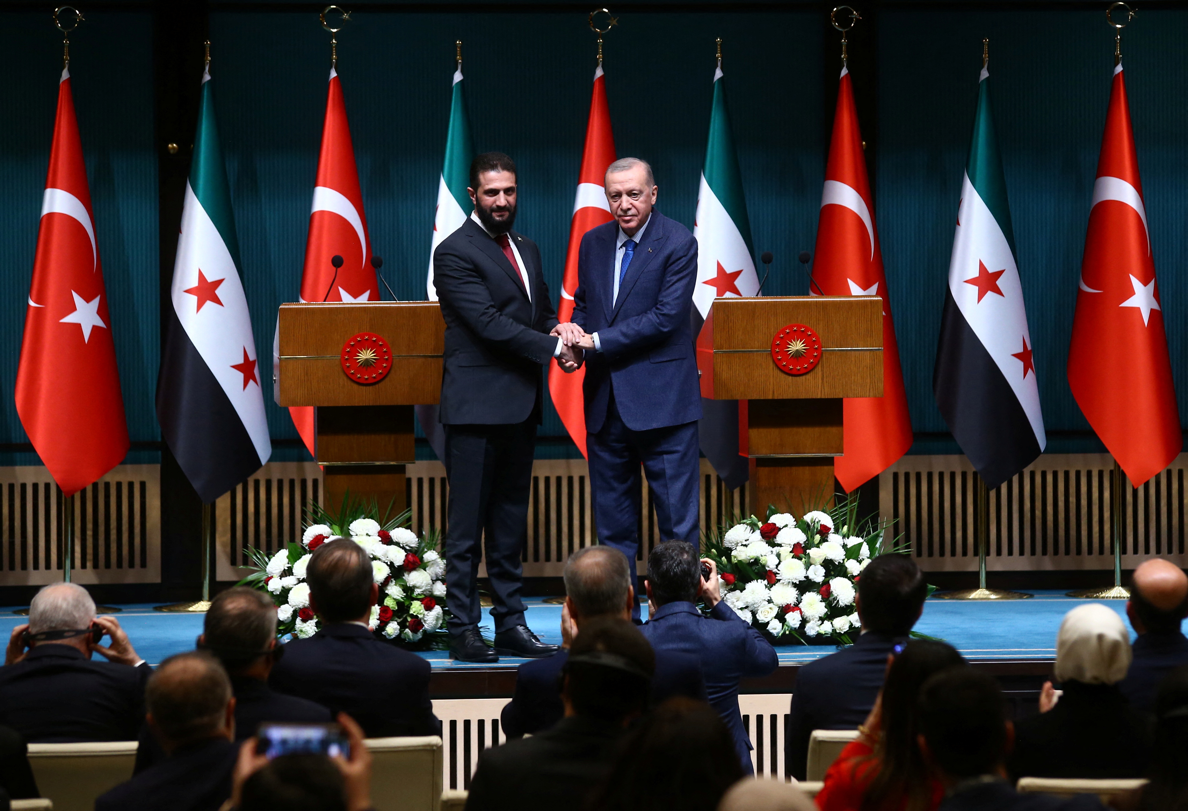 Syria's newly appointed president for a transitional phase Ahmed al-Sharaa and Turkey's President Tayyip Erdogan pose as they shake hands after a joint press conference at the Presidential Palace in Ankara, Turkey