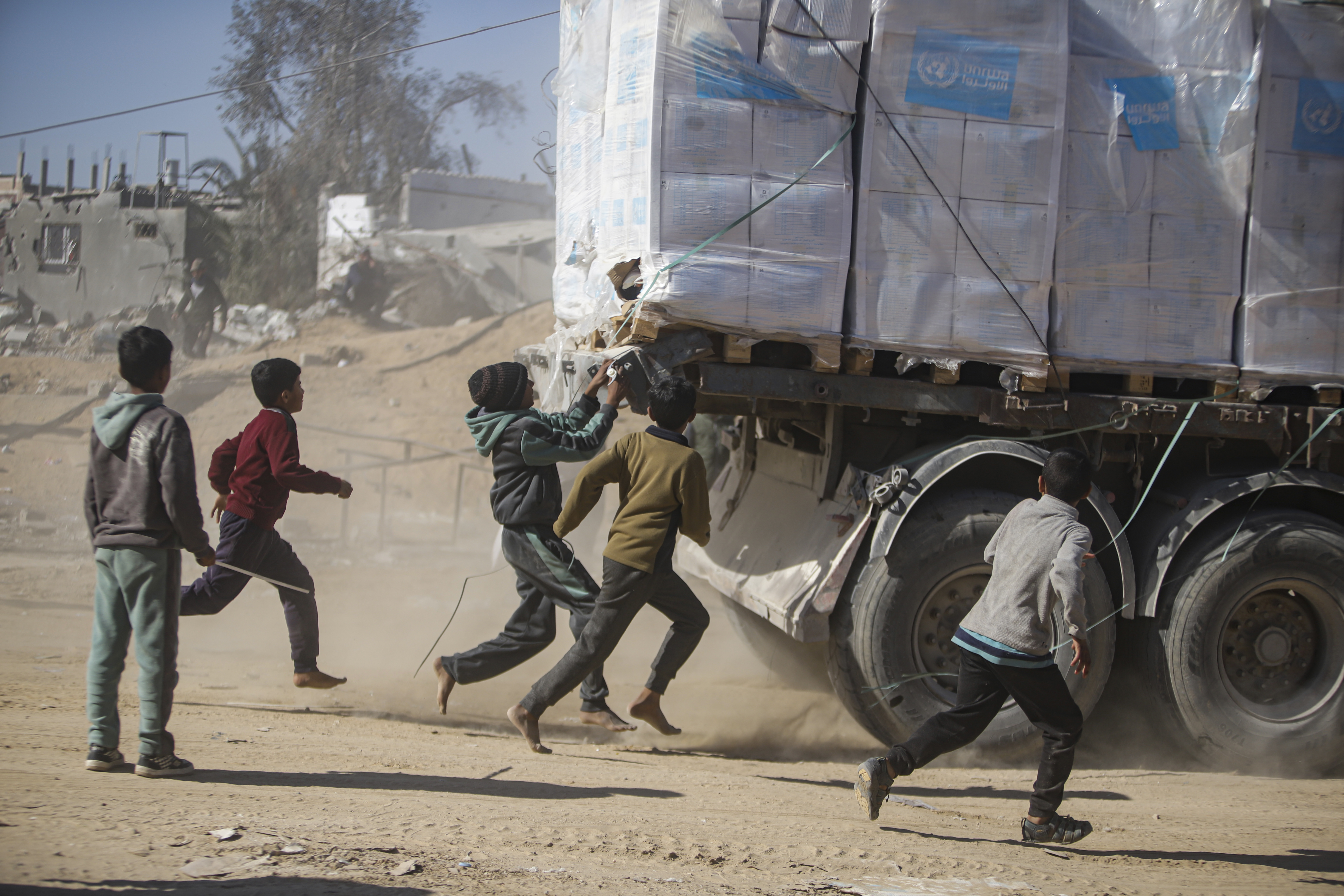 Palestinians chase humanitarian aid trucks.