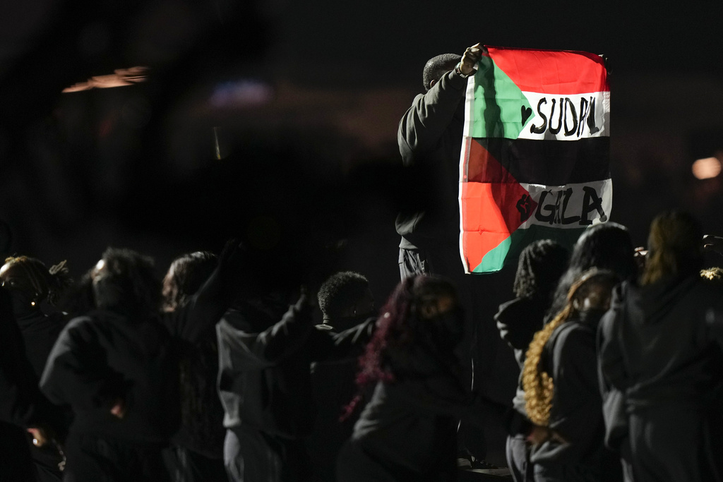 a person holds.a red green and black flag that says Sudan Gaza