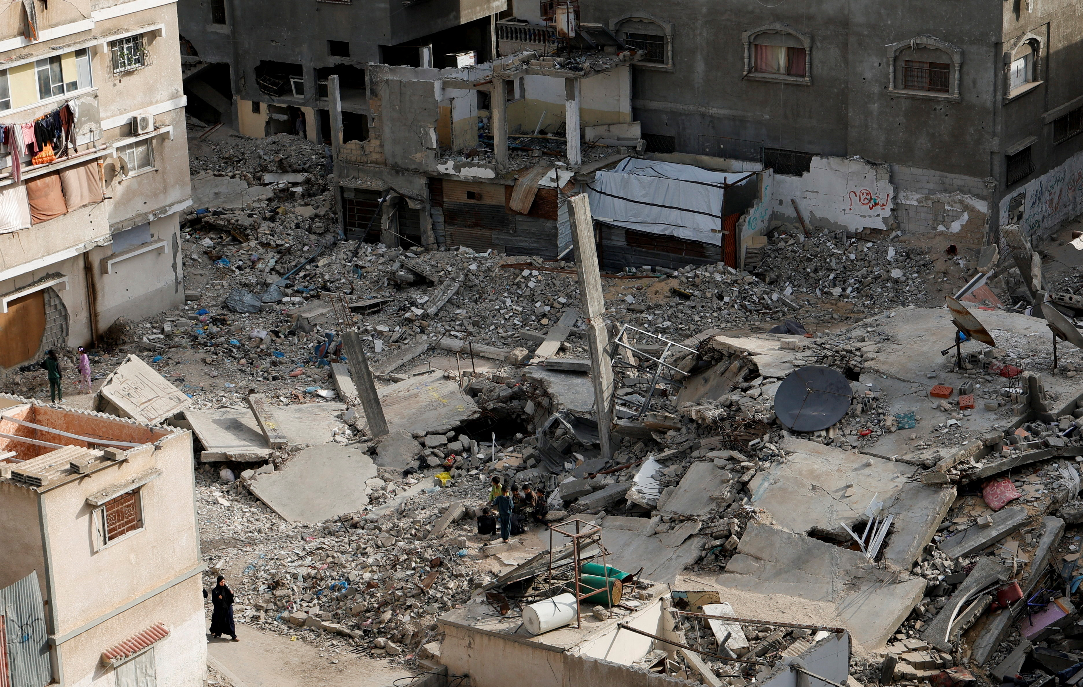 A Palestinian woman walks near the rubble of houses, in Khan Younis in the southern Gaza Strip. [Hatem Khaled/Reuters] (Reuters)