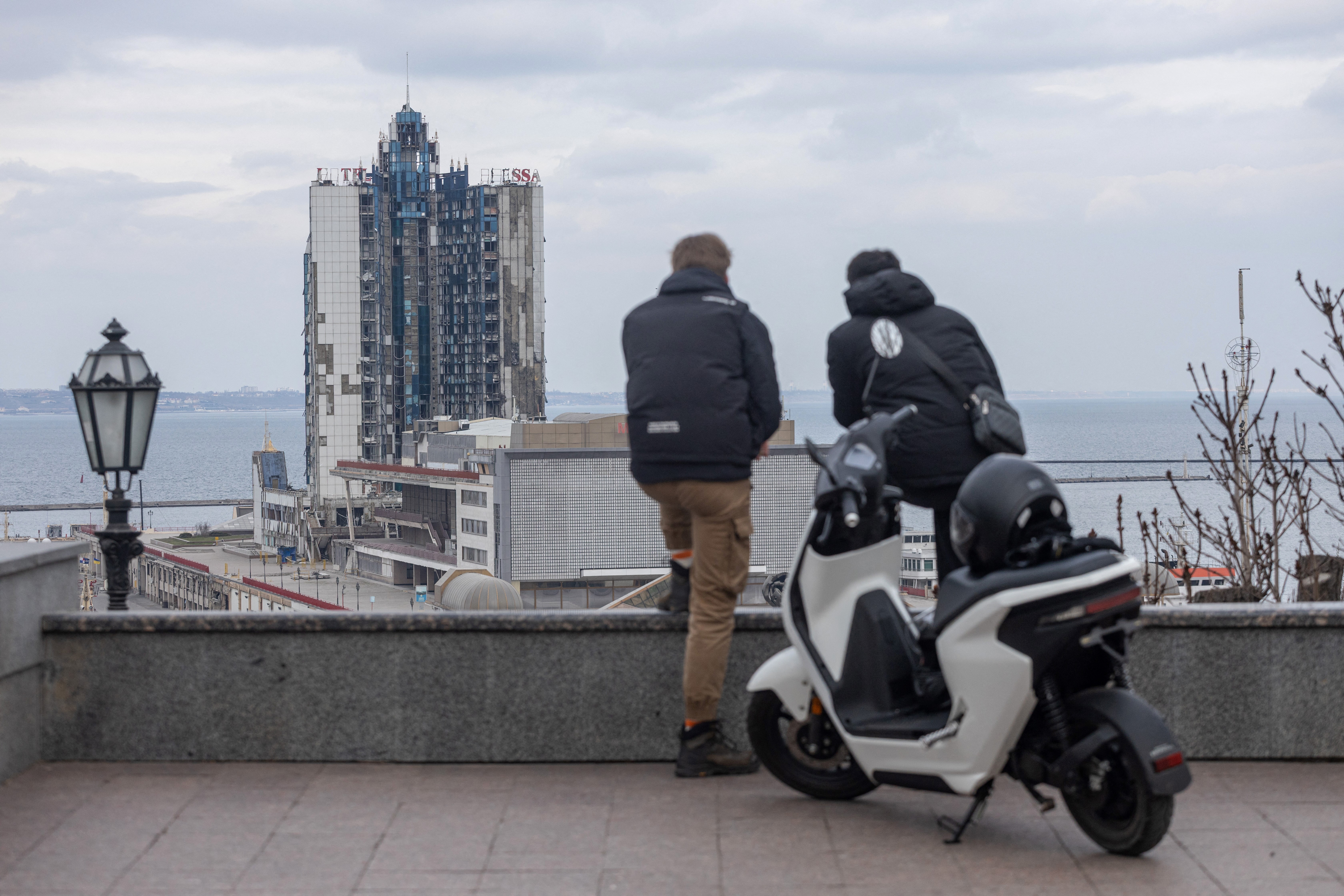 Two man stand looking towards the damaged nineteen-story hotel "Odessa", in the port city of Odesa, on the Black Sea in southern Ukraine [File: Oleksandr Gimanov/AFP]