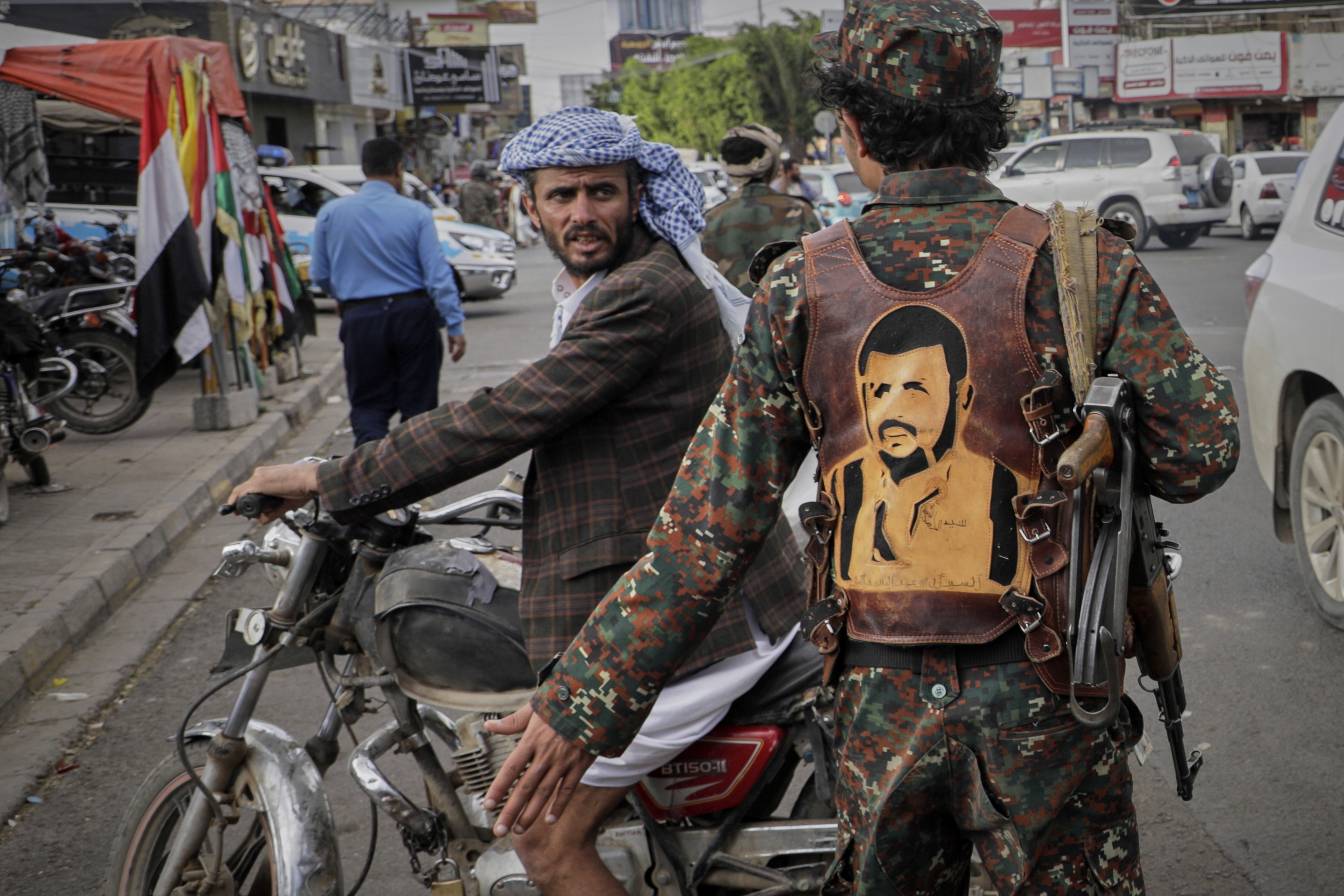 A Houthi fighter wears a vest showing a drawing of the leader of the Houthi movement Abdul Malik al-Houthi as he directs traffic