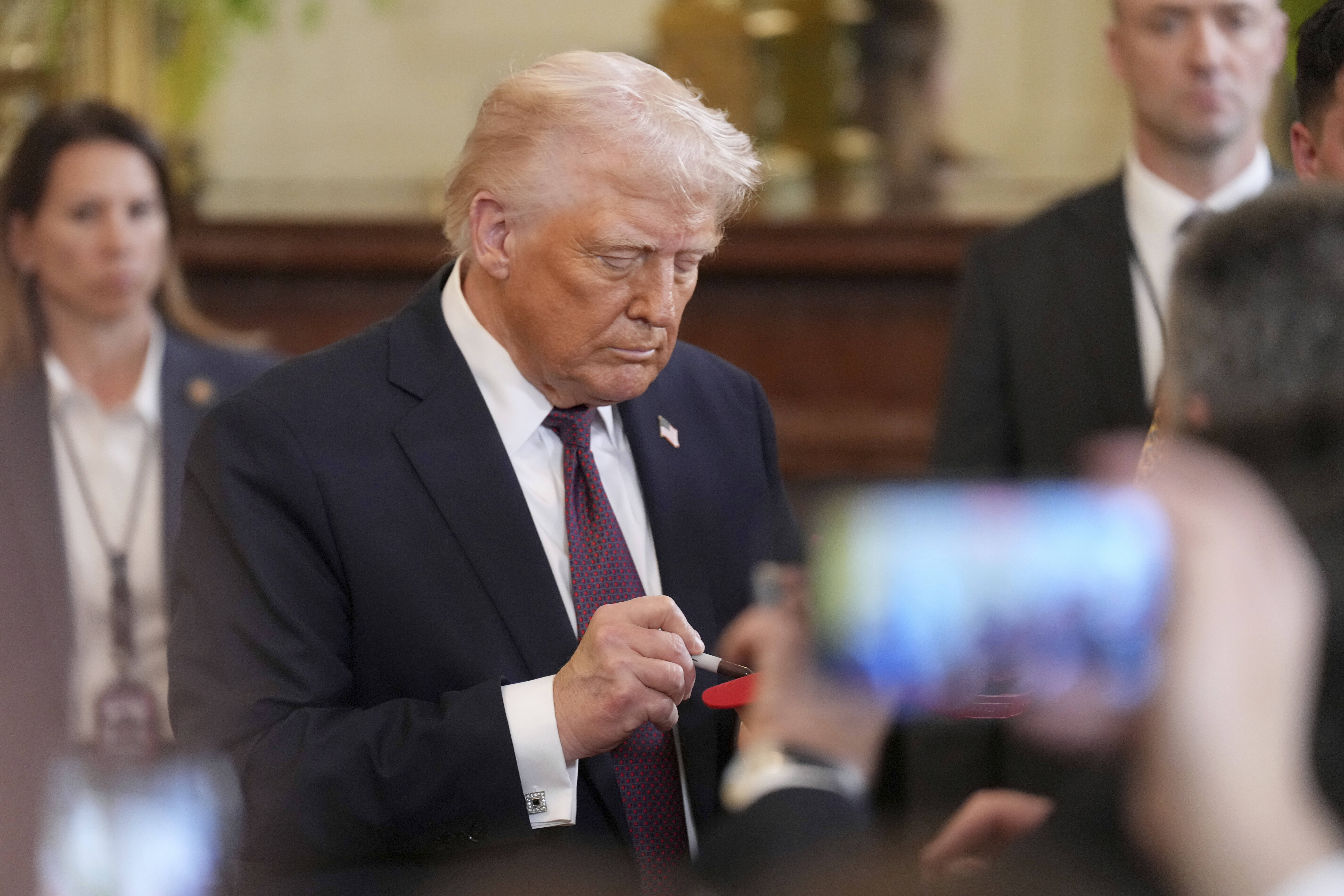 Onlookers take cellphone photos of Donald Trump in the White House.