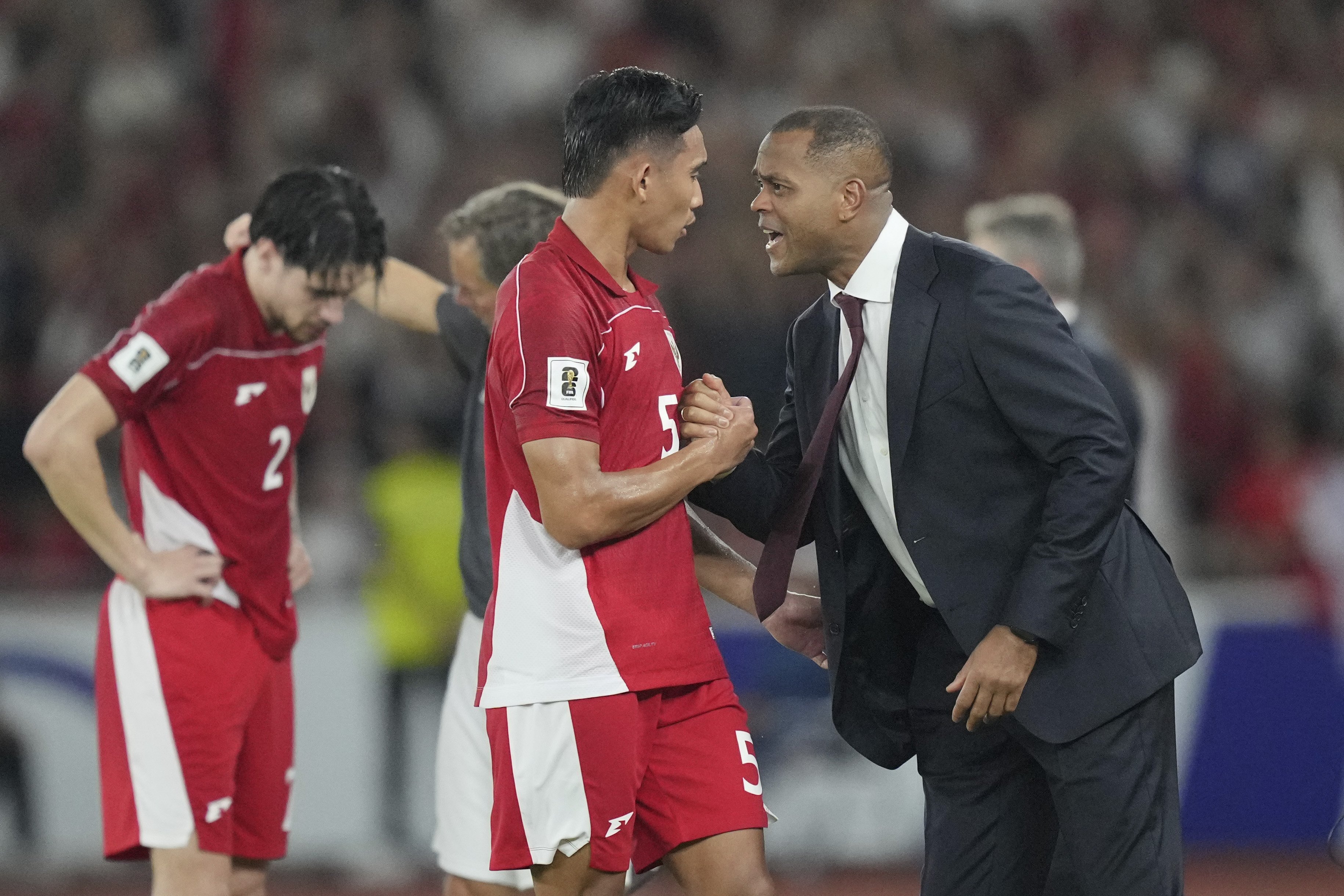 Indonesia's head coach Patrick Kluivert, right, talks to Indonesia's Rizky Ridho Ramadhani during the third round of the 2026 World Cup Group C Asia qualifier soccer match between Indonesia and Bahrain at Gelora Bung Karno Main Stadium in Jakarta, Indonesia, Tuesday, March 25, 2025. (AP Photo/Tatan Syuflana)