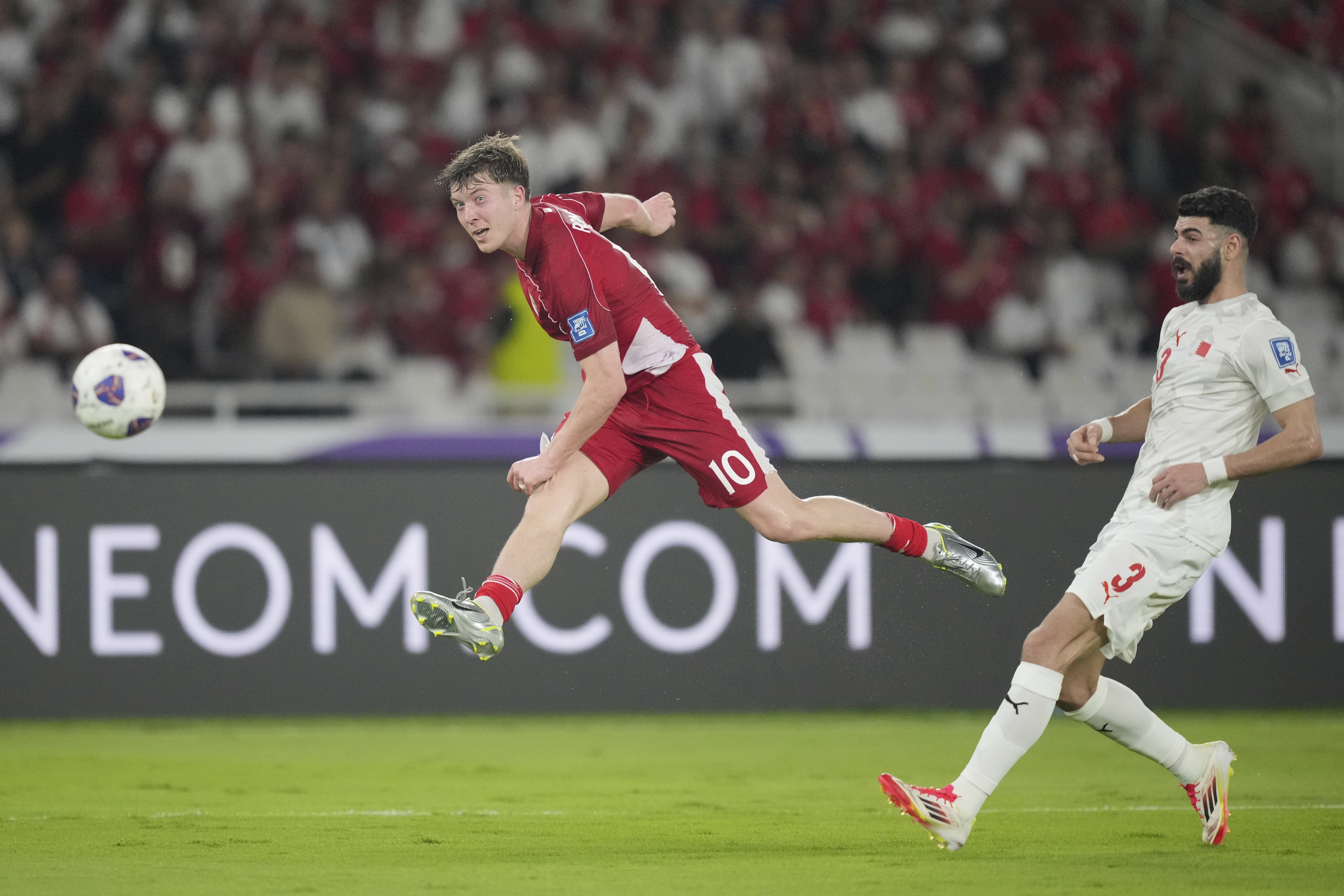 Indonesia's Ole Lennard Romenij, left, shoots past Bahrain's Waleed Alhayam during a World Cup 2026 group C Asia qualifying soccer match between Indonesia and Bahrain at Gelora Bung Karno Main Stadium in Jakarta, Indonesia, Tuesday, March 25, 2025. (AP Photo/Tatan Syuflana)