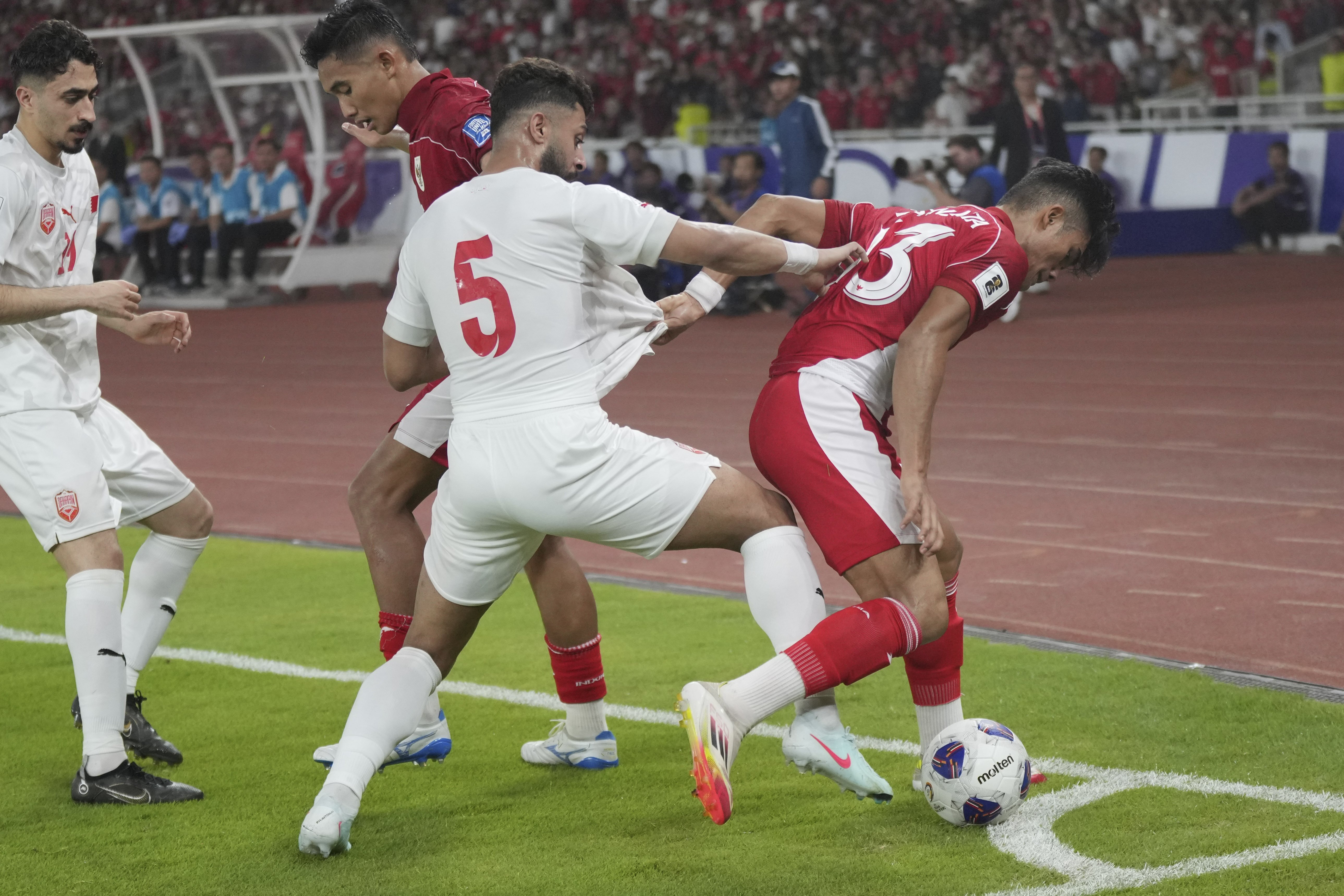 Indonesia's Ramadhan Sananta, right, battles for the ball against Bahrain's Husain Aleker during a World Cup 2026 group C Asia qualifying soccer match between Indonesia and Bahrain at Gelora Bung Karno Main Stadium in Jakarta, Indonesia, Tuesday, March 25, 2025. (AP Photo/Tatan Syuflana)
