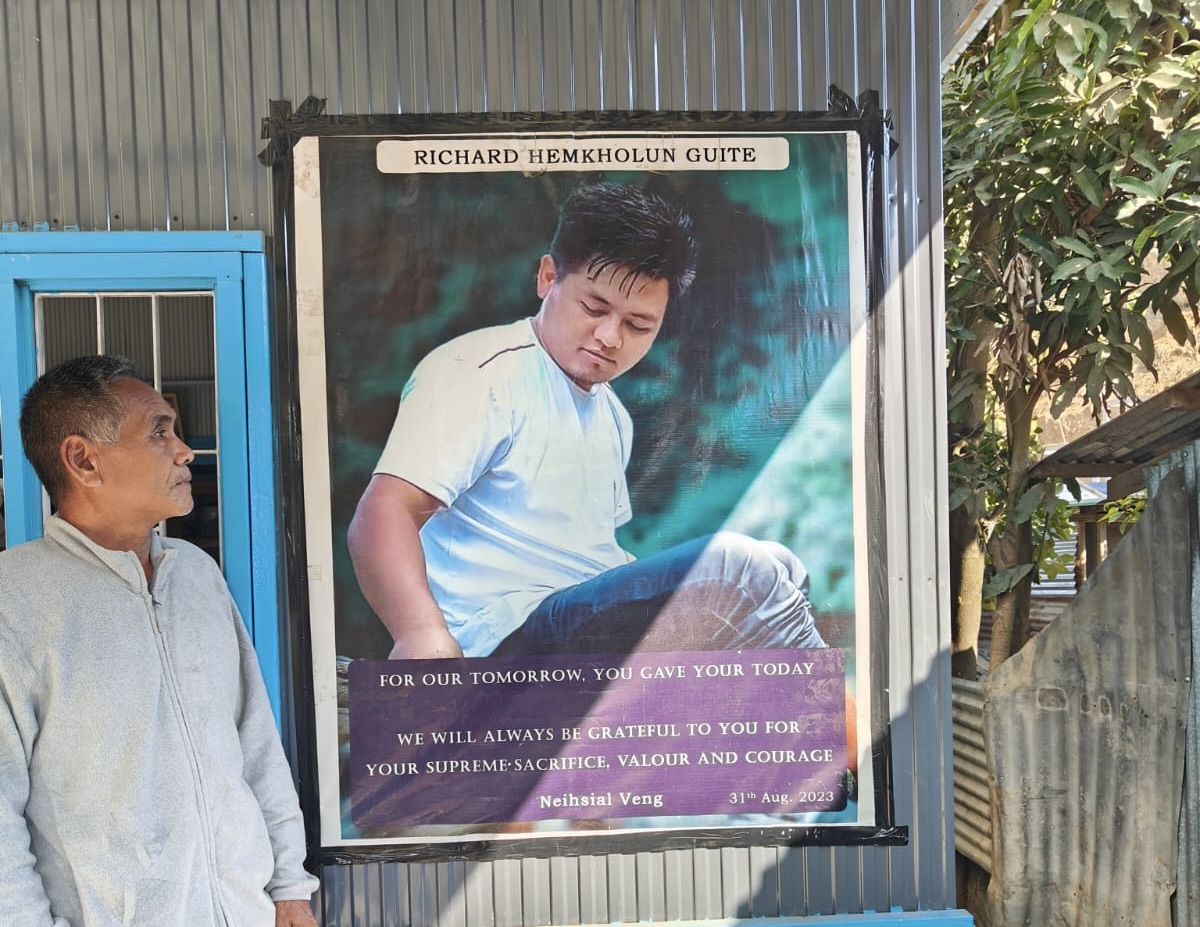 Richard's 70-year-old grandfather, P.T. Neissia, stands before his grandson's memorial poster