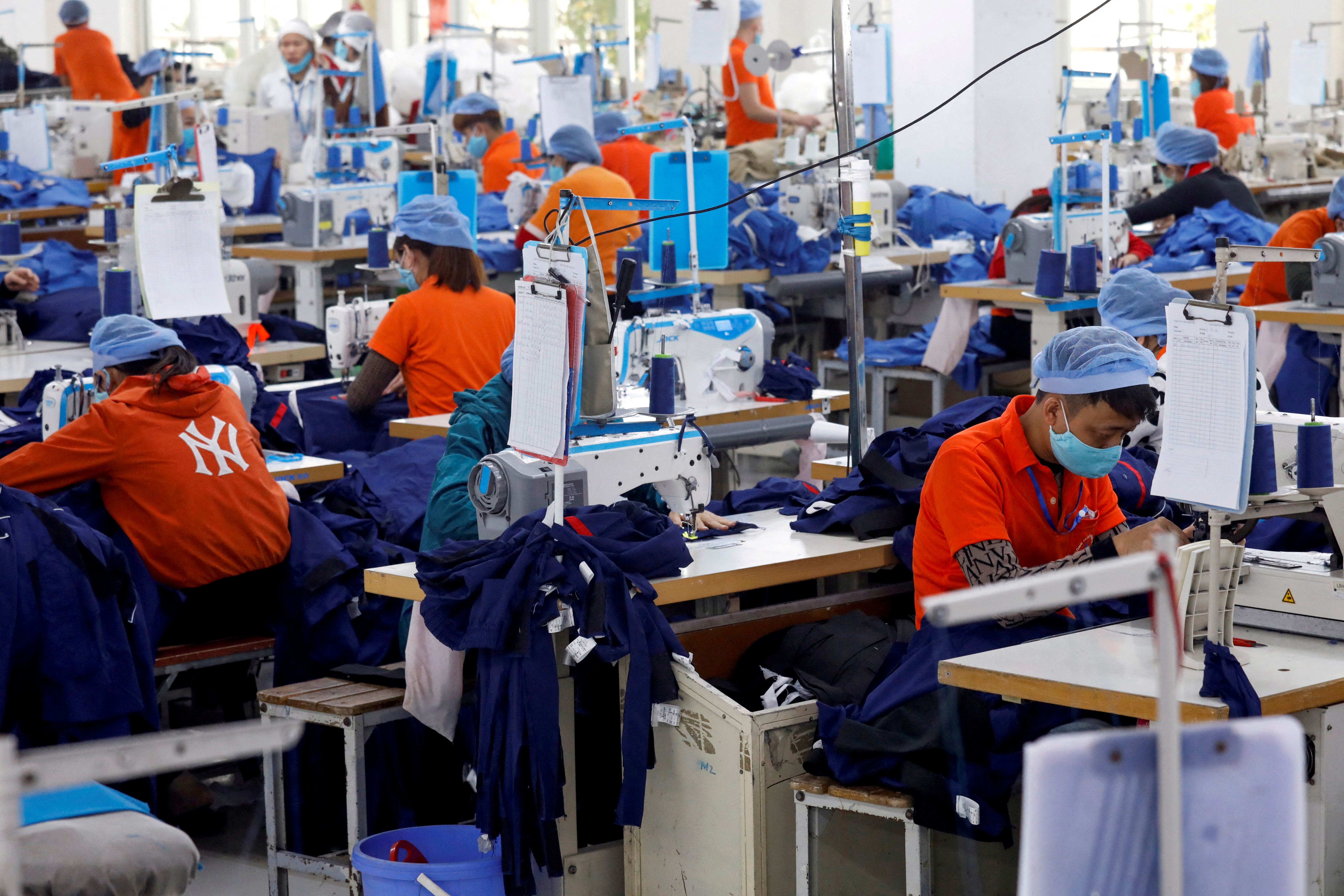vietnam garment workers hunch over sewing machines